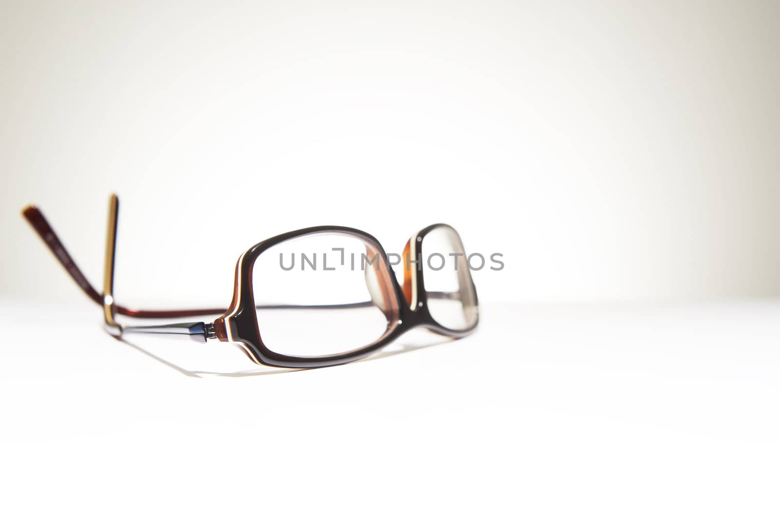 A pair of classic framed reading glasses resting on a white background with space for text
