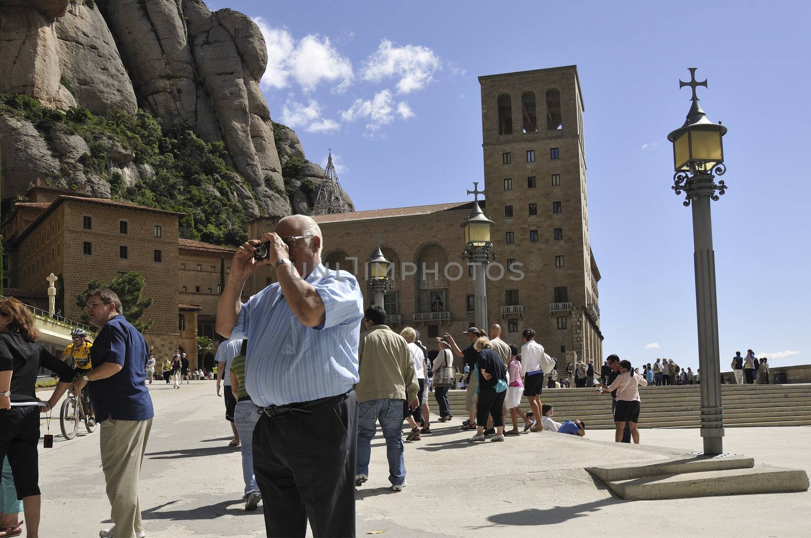 Barcelona, Spain - June 20, 2010 :  man takes photo among walking tourists at the place of famous Monserrat Monastery at Barcelona's vicinity.