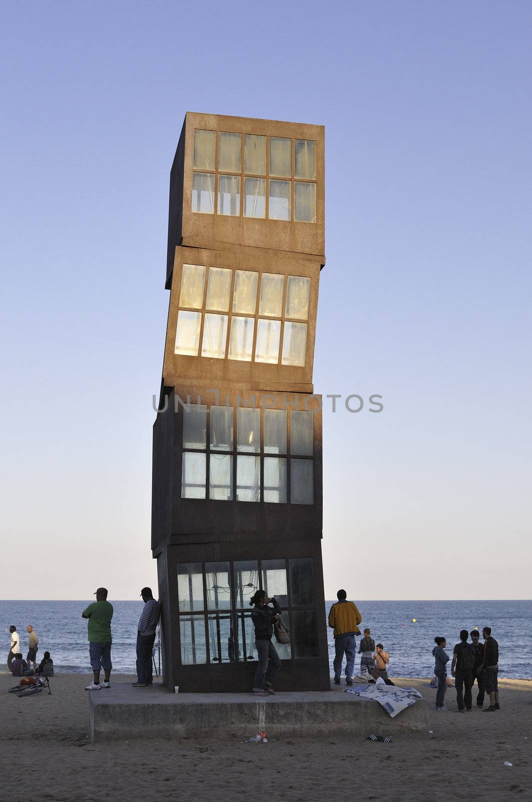 Barcelona, Spain - June 21, 2010 : people rest on the famous Berceloneta beach at evening close to "Homage to Barceloneta" modern art sculpture made by Rebecca Horn.