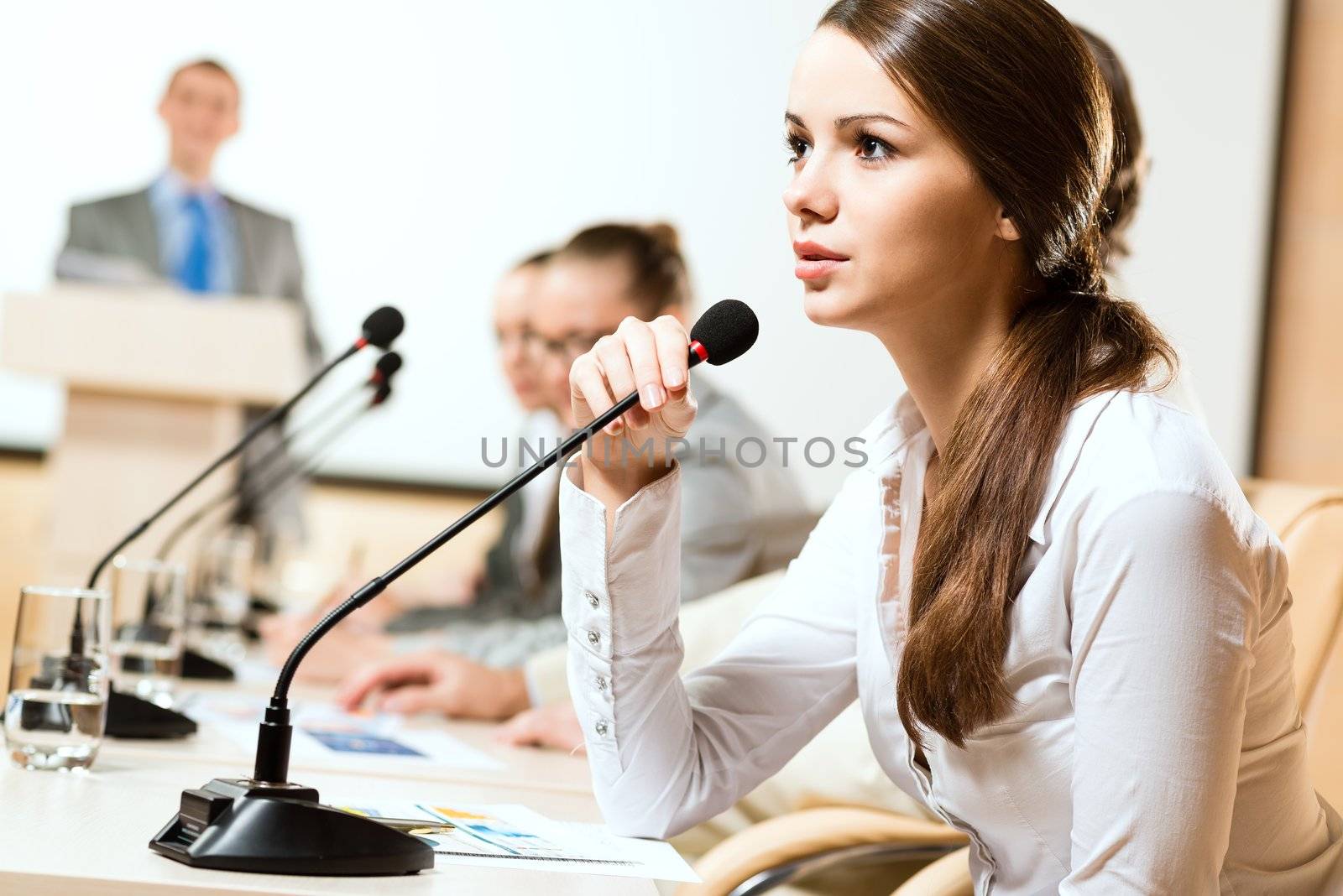 Business woman speaks into a microphone, communication businessmen at a conference