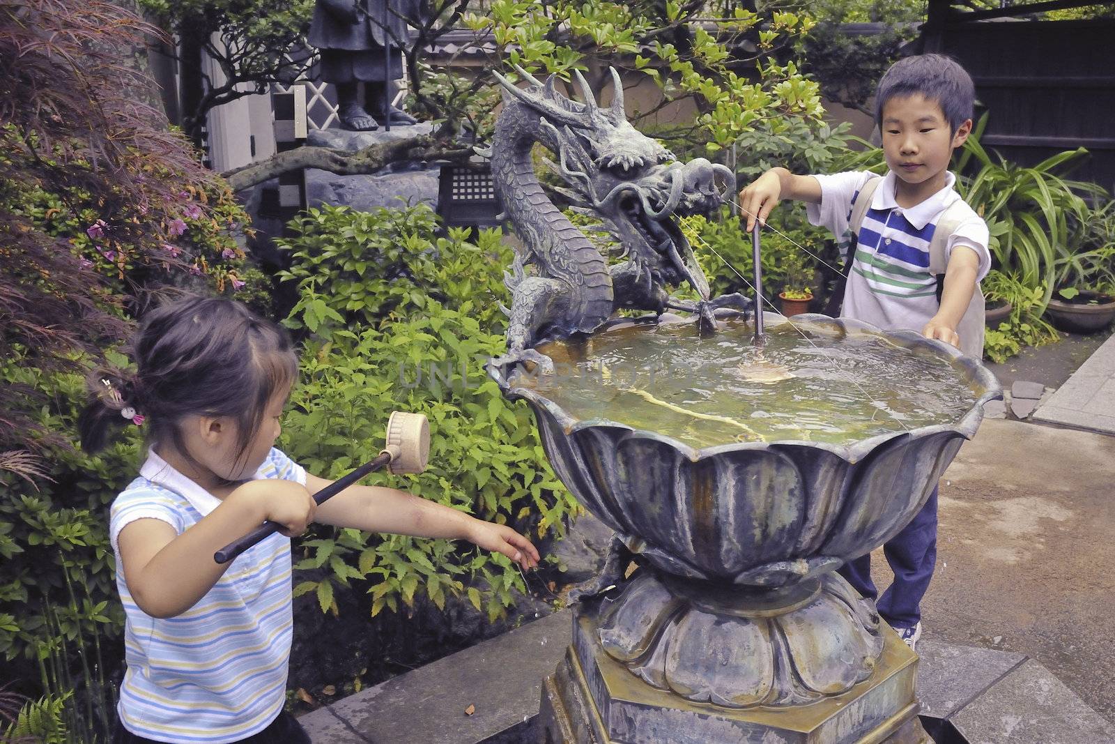 Kamakura, Japan -June 21, 2008: Japanese children wash hands in traditional water source before entrance to Buddhist temple