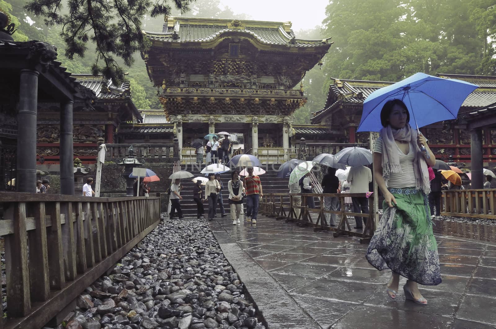 Nikko, Tochigi, Japan - June 22, 2008: Visitors walks under rain on the place of famous Toshogu shrine. The Toshogu is famous as a mausoleum of Tokugawa Ieyasu, founder of the Tokugawa shogunate, which ruled Japan for over 250 years until 1868.