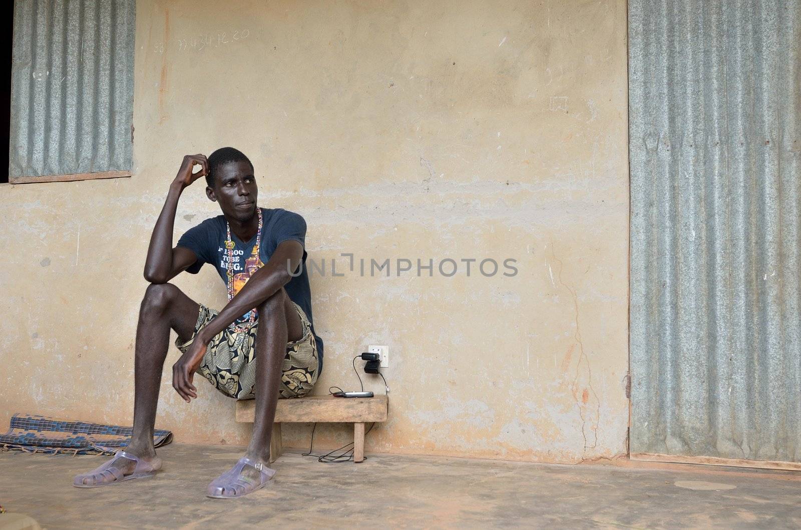 KARTIAK, SENEGAL - SEPT 18:Un adolescent African and not identified sat in the terrace, of his humble house, September 18 th 2012 in Kartiak, Senegal. The region of Casamance, south of Senegal is a very poor area according to International statistic