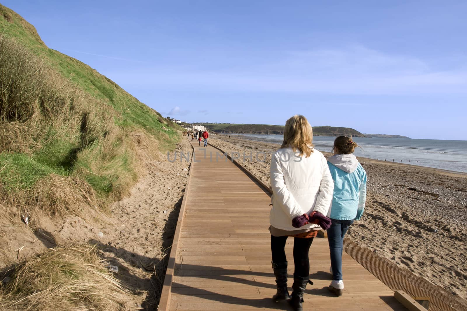 mother and daughter on beach boardwalk by morrbyte