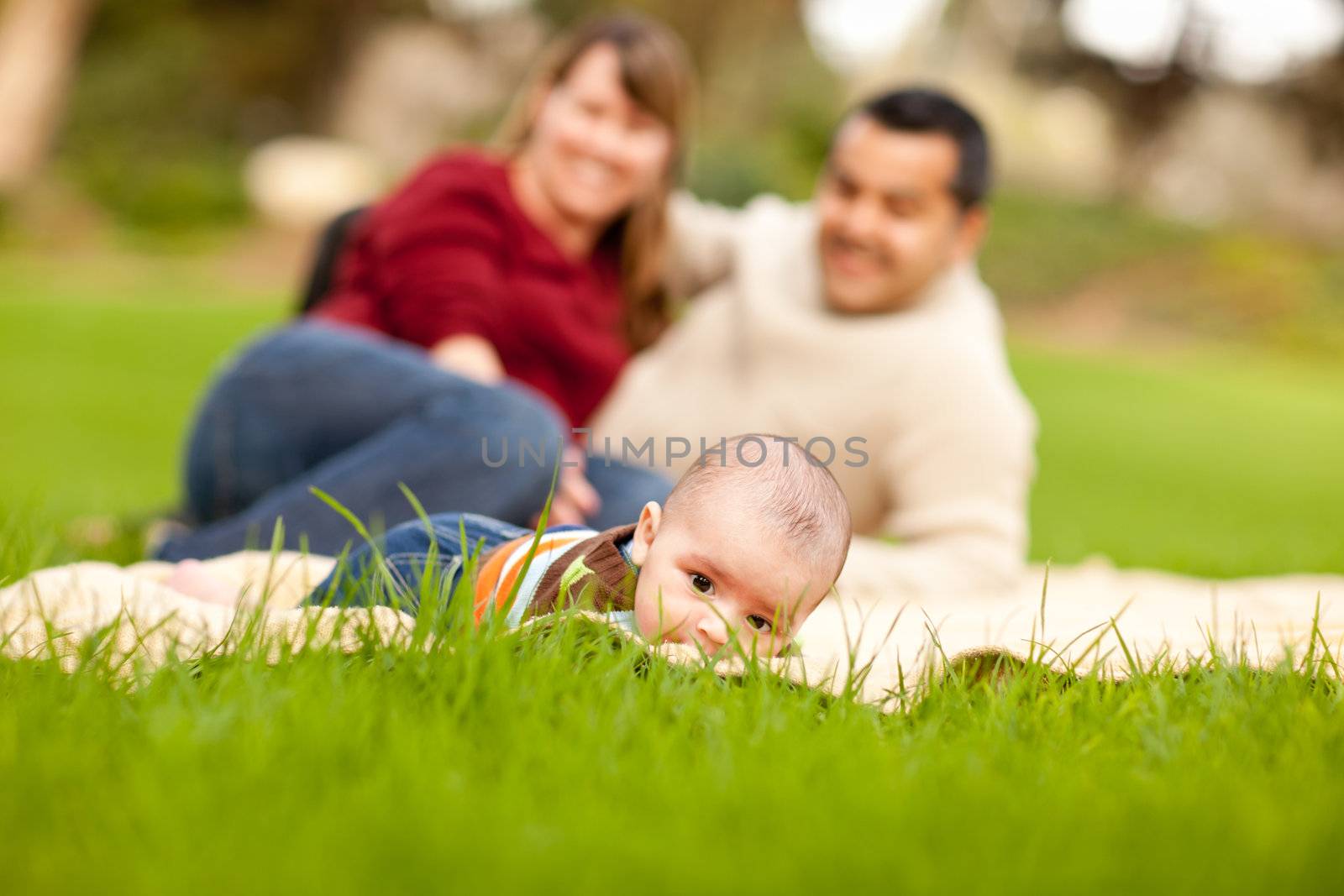 Happy Crawling Baby Boy and Mixed Race Parents Playing in the Park.