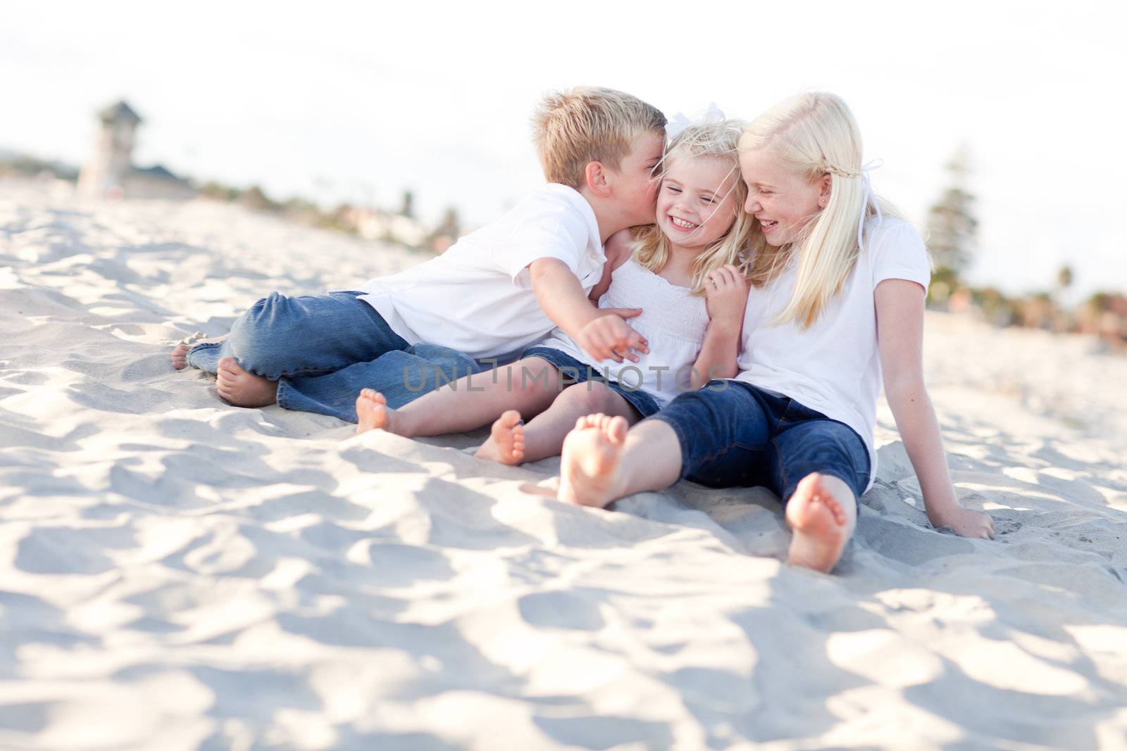 Adorable Sibling Children Kissing the Youngest at the Beach.