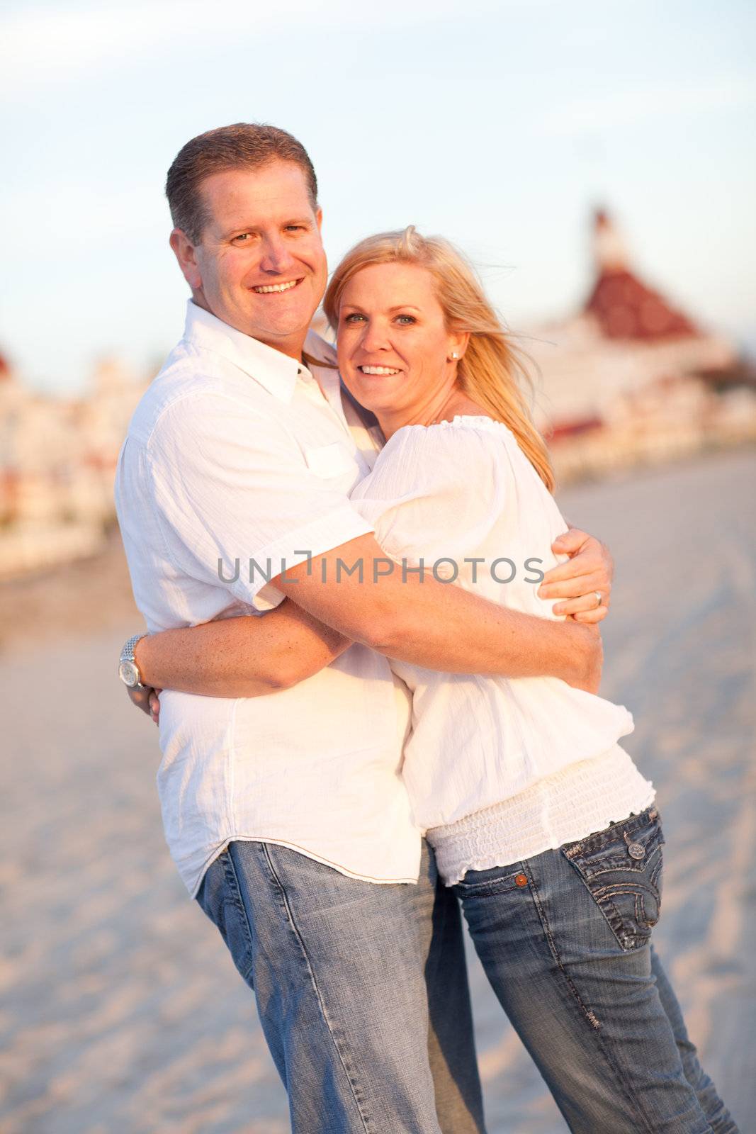 Attractive Caucasian Couple Hugging at the Beach in Front of the Hotel Del Coronado, San Diego, CA.