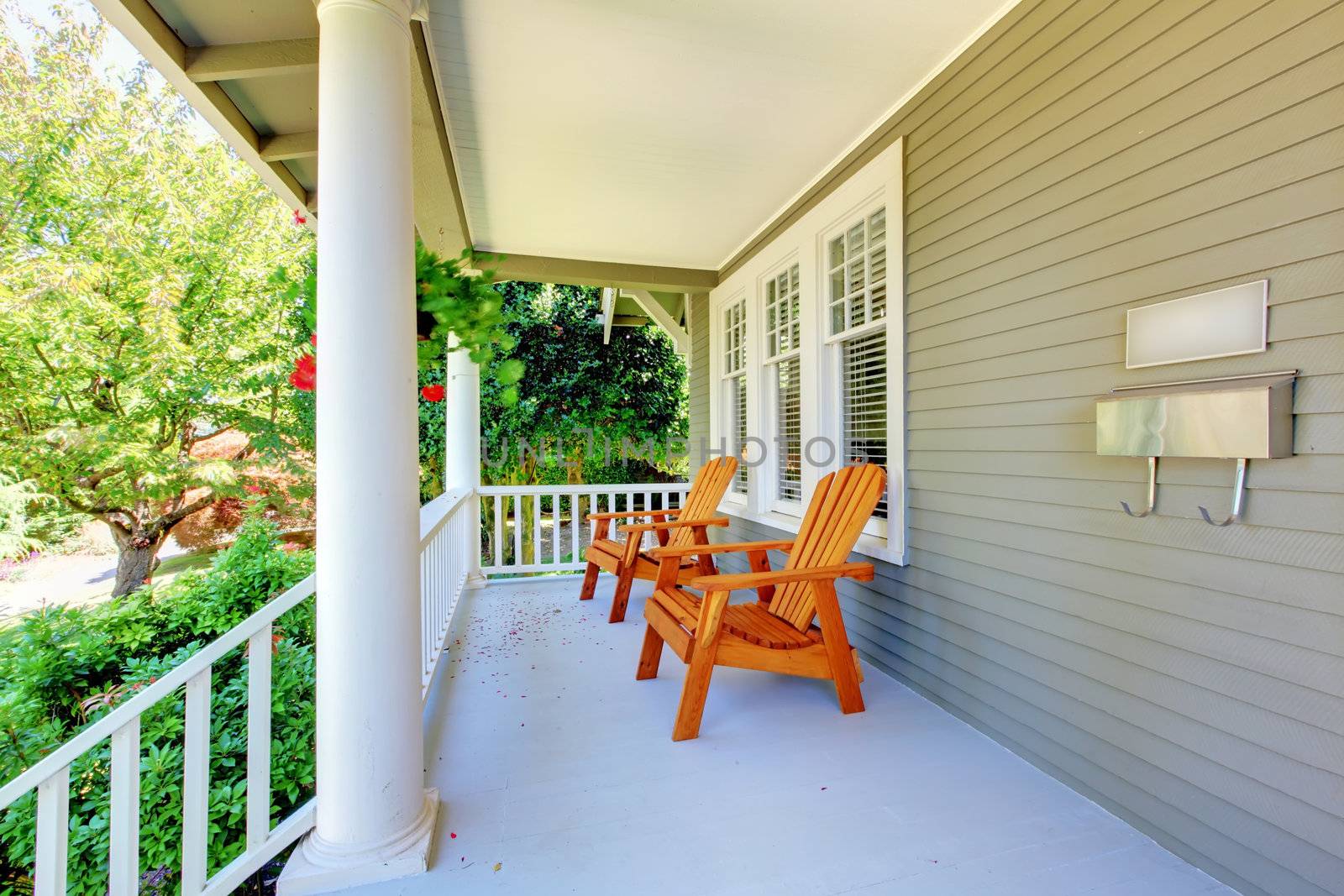 Front porch with chairs and columns of old craftsman style home.