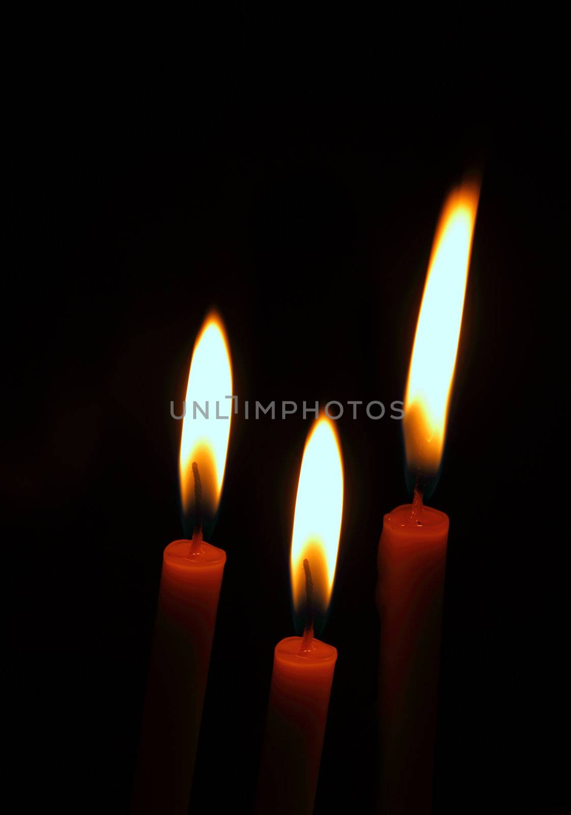 three burning candles on a black background