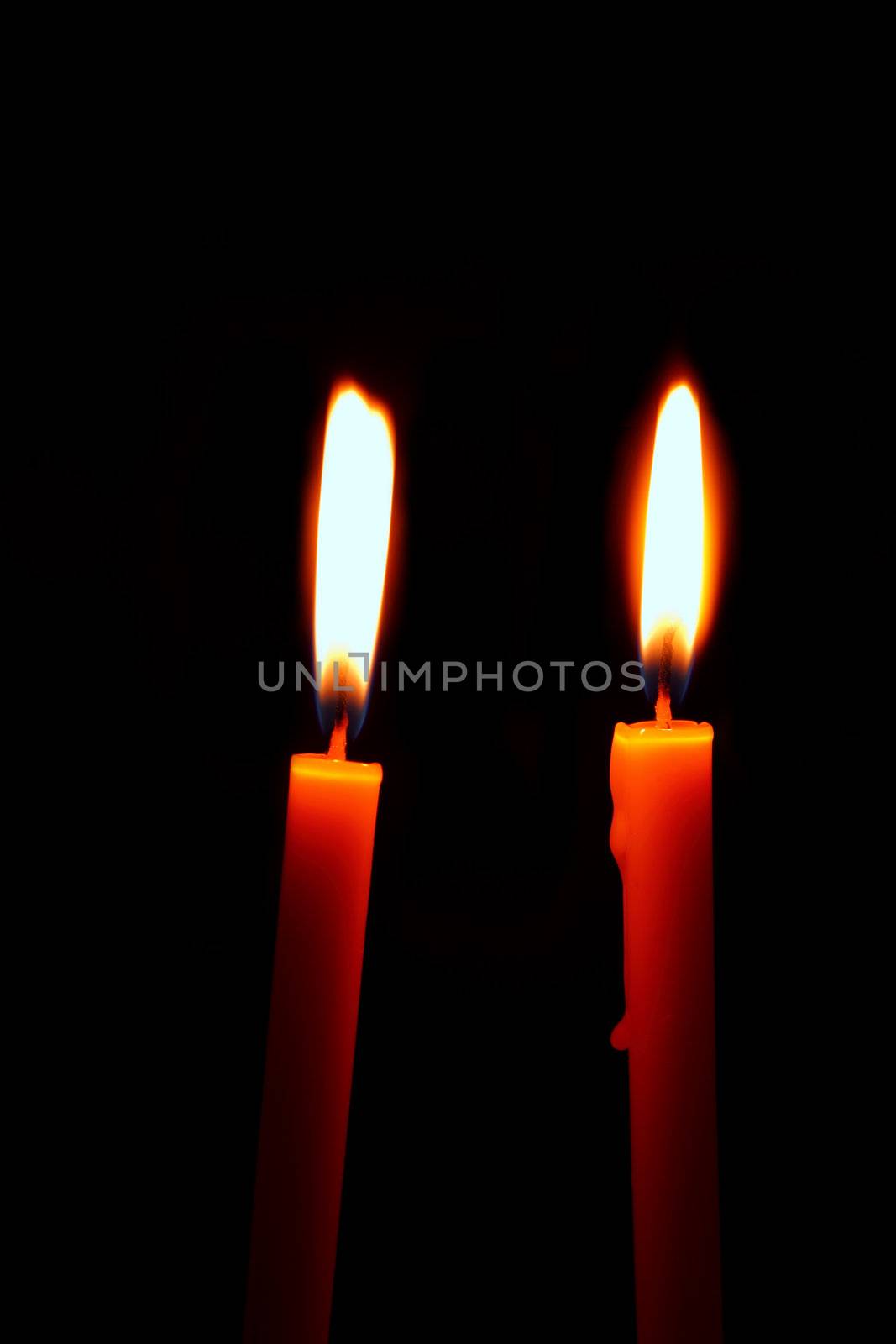 two burning candles on a black background