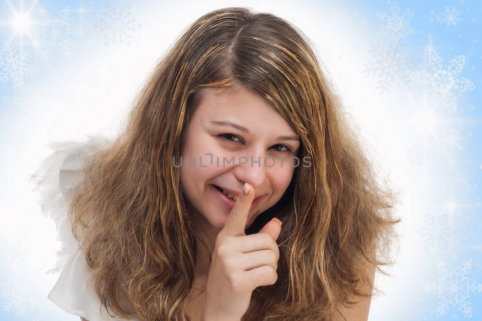 smiling christmas angel with golden hair and wings holding finger on lips on white blue background with stars and snow