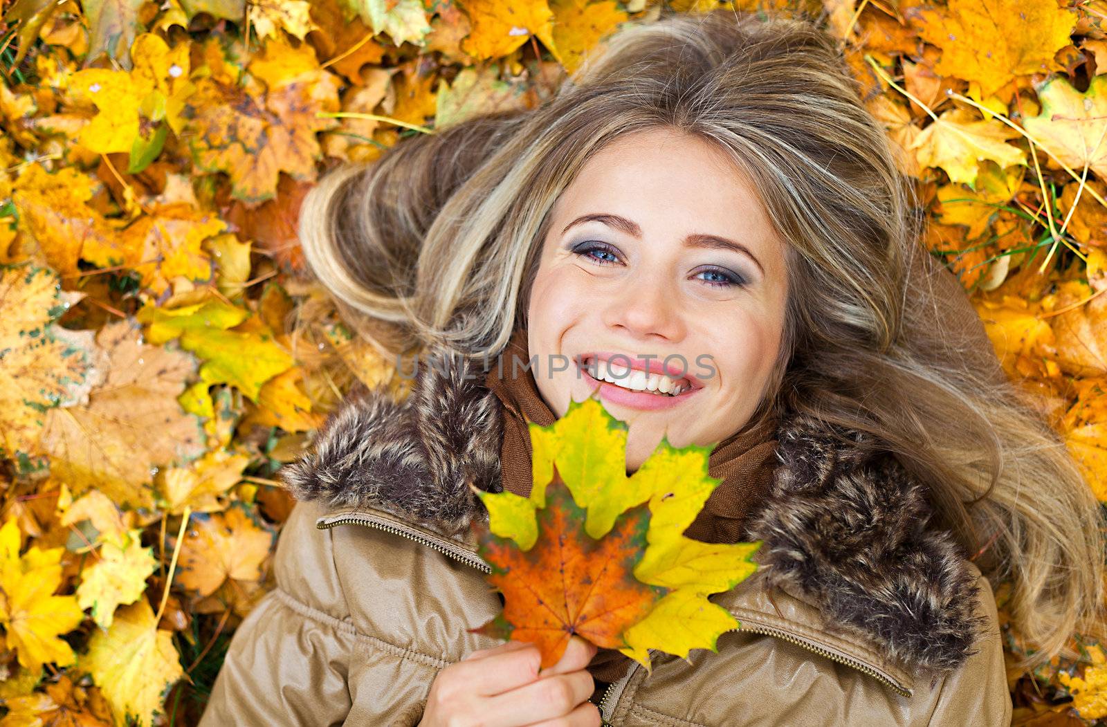 Closeup portrait of a young woman surrounded by autumn leaves