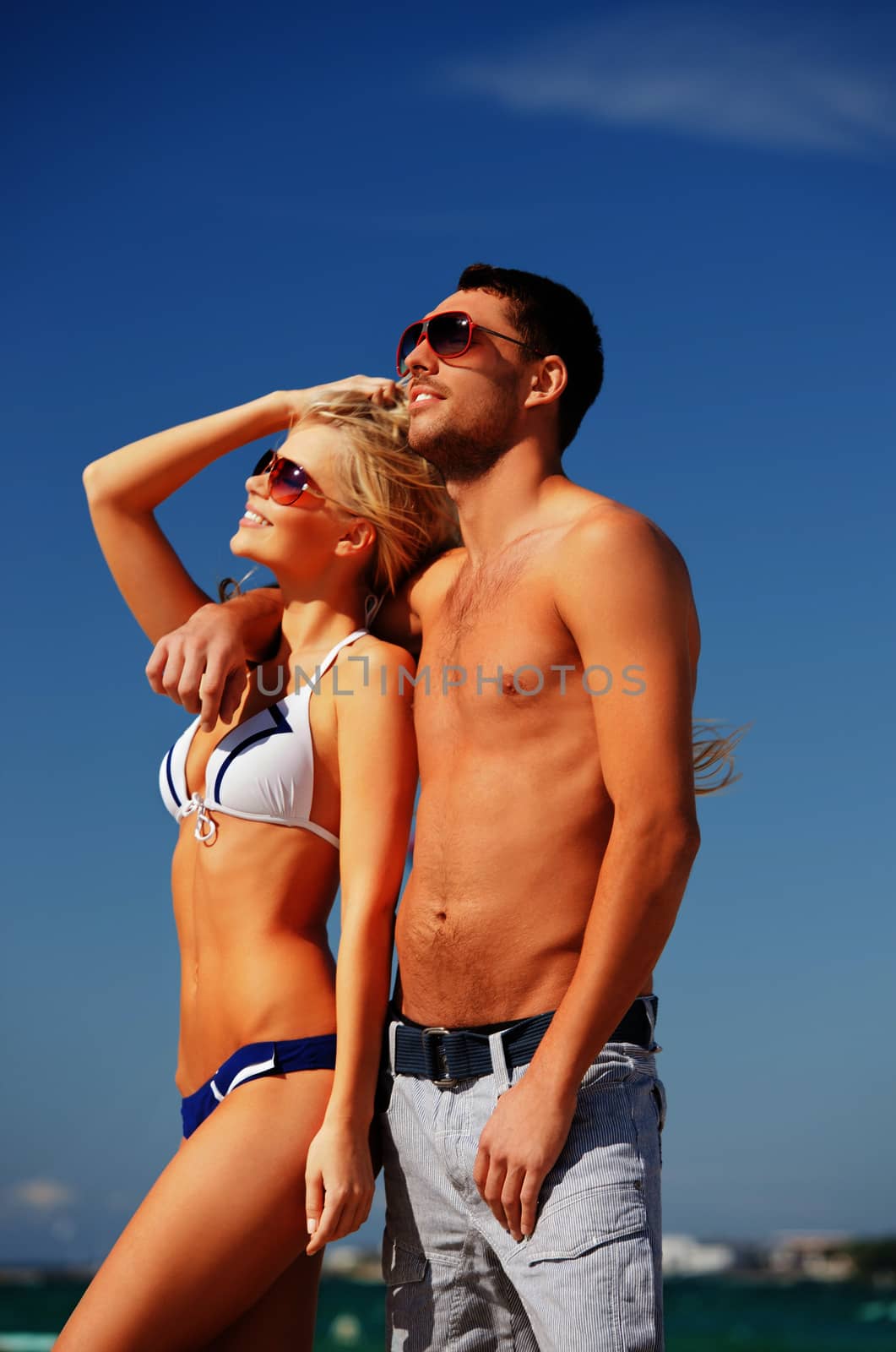 happy couple in sunglasses on the beach by dolgachov