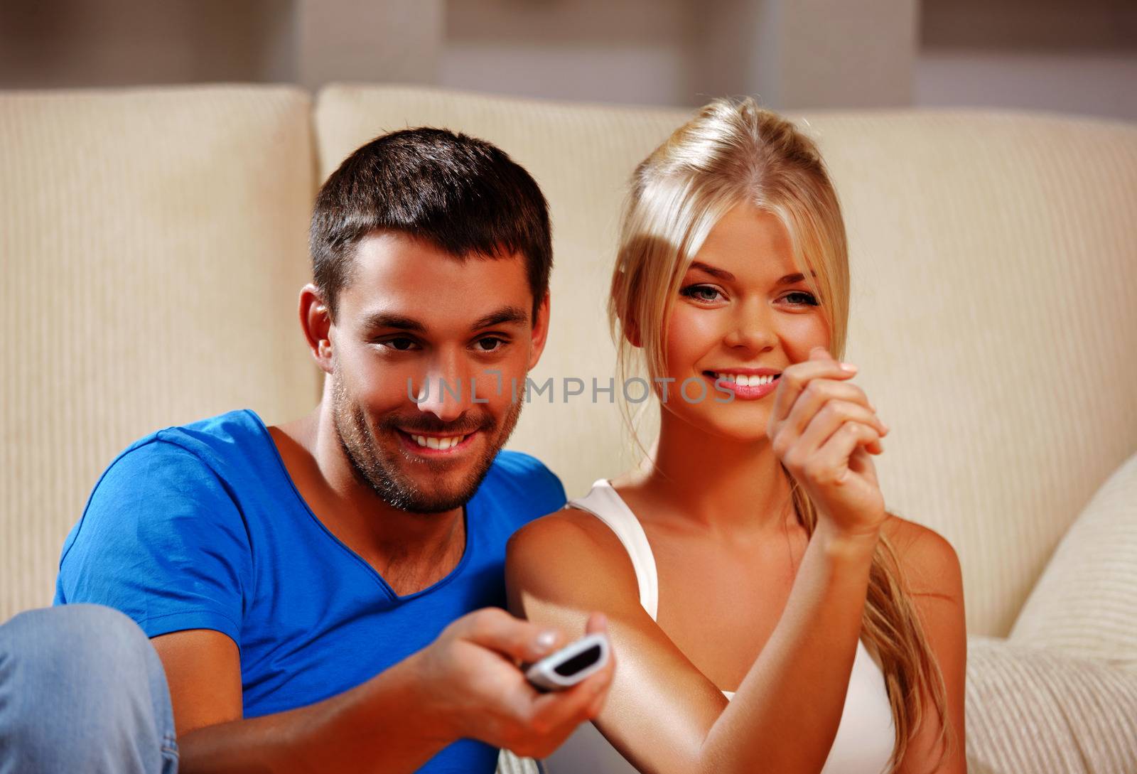 happy romantic couple with TV remote by dolgachov