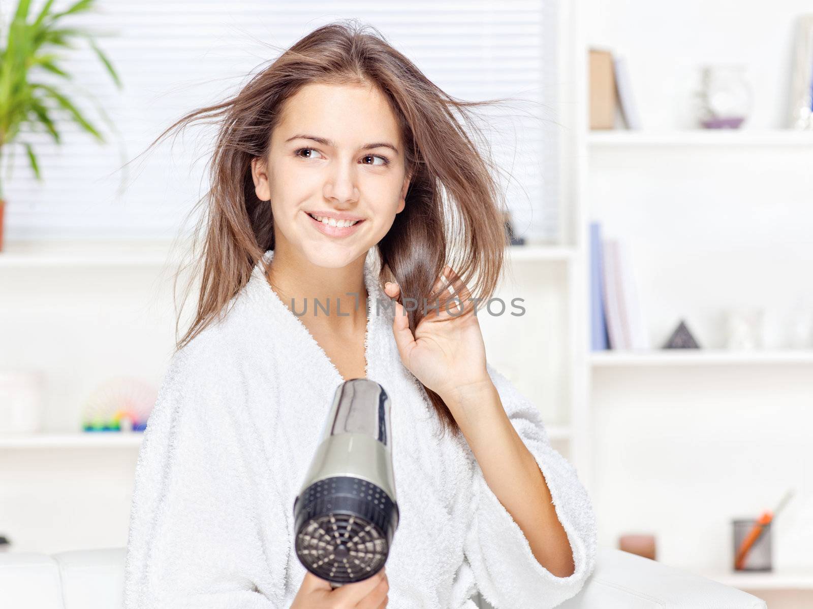 Young woman drying hair at home