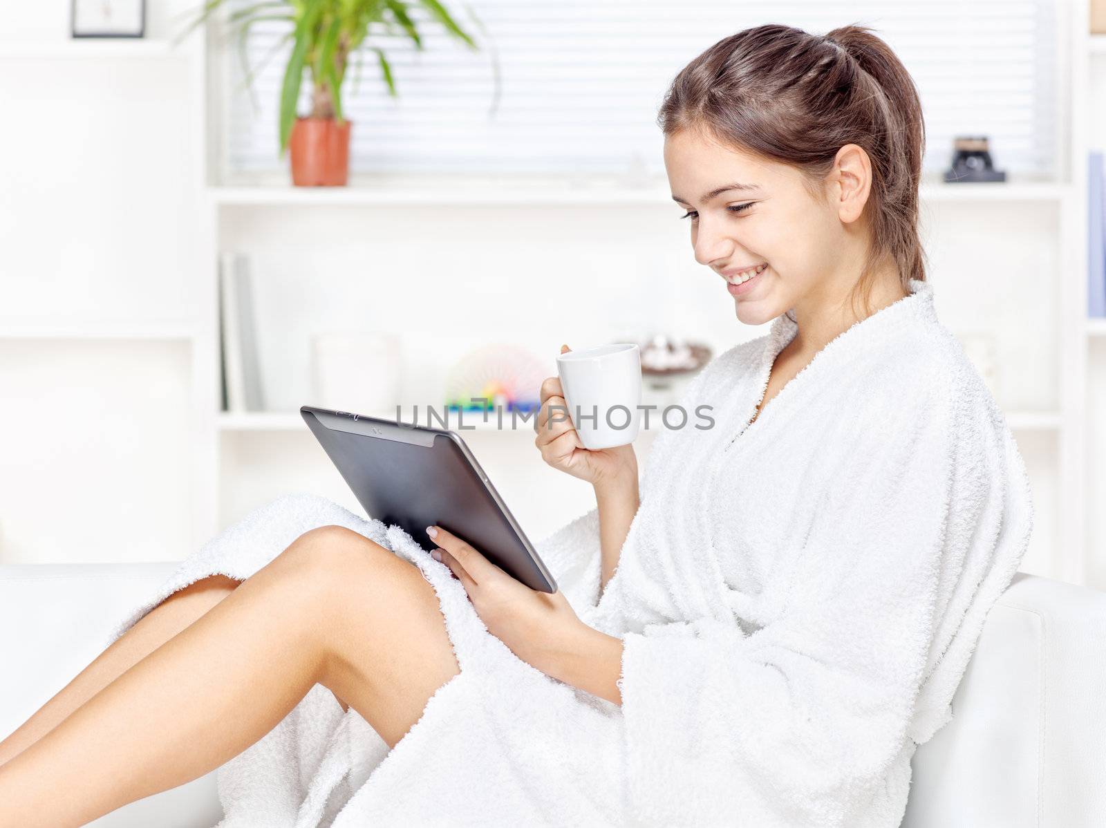 girl in bathrobe at home with touch pad computer and drink
