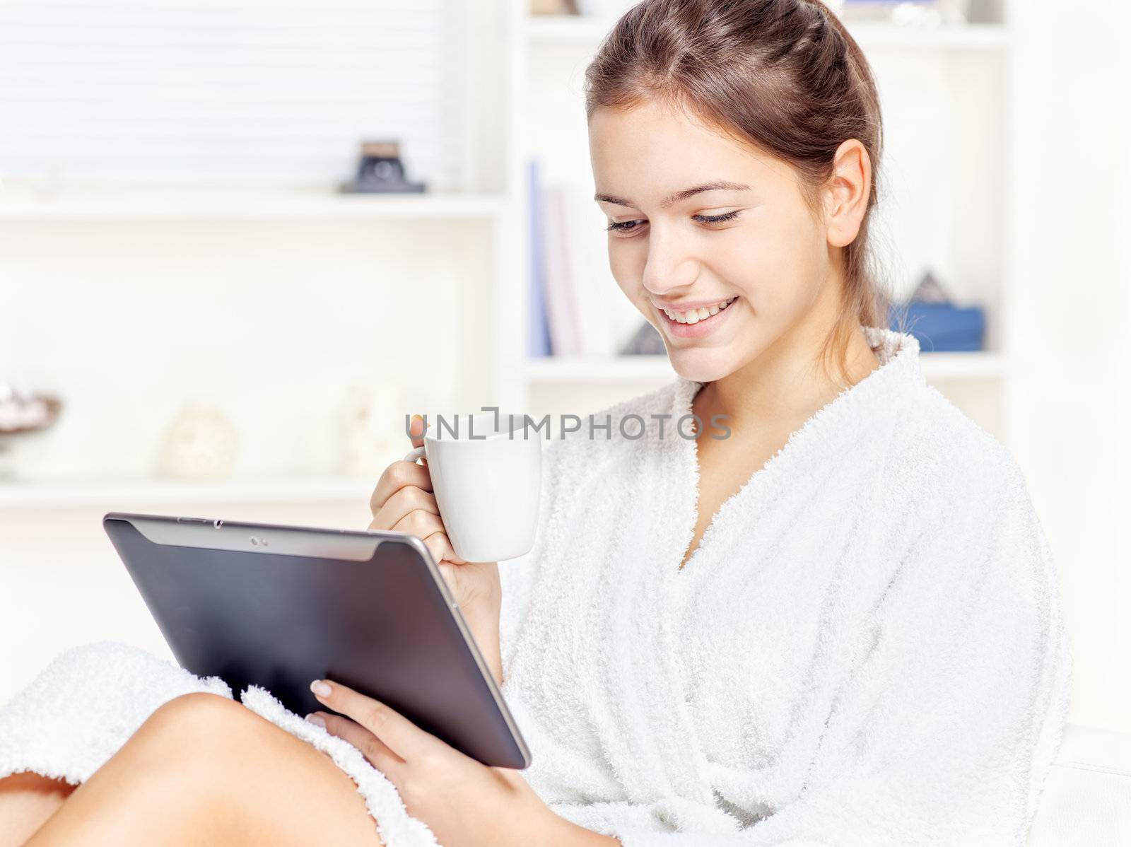 girl in bathrobe at home with touch pad computer and drink