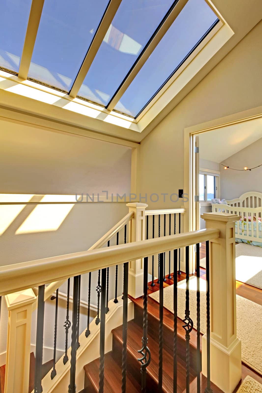 Staircase with skylight and baby room in a bright hallway.