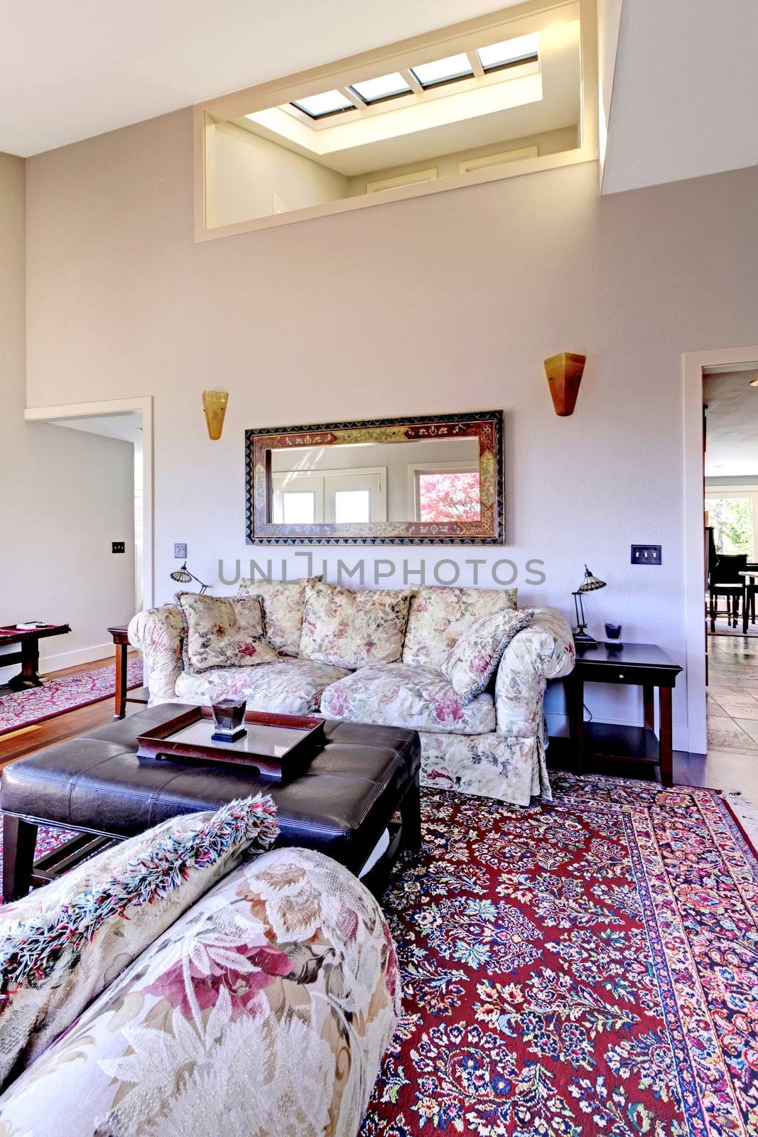 Living room with high ceiling with red rug and sofas.