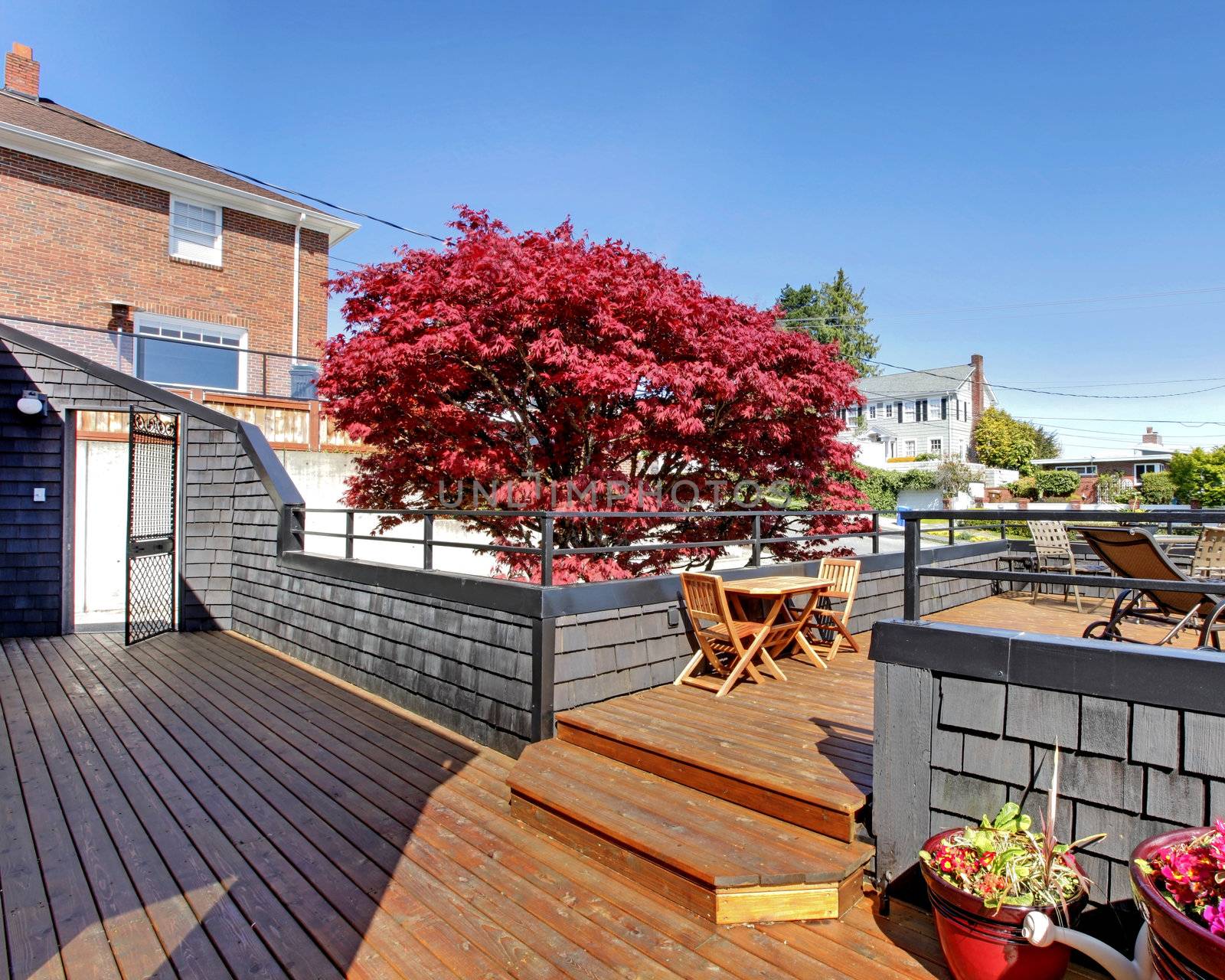 Large outdoor terrace with furniture in the front of the house.