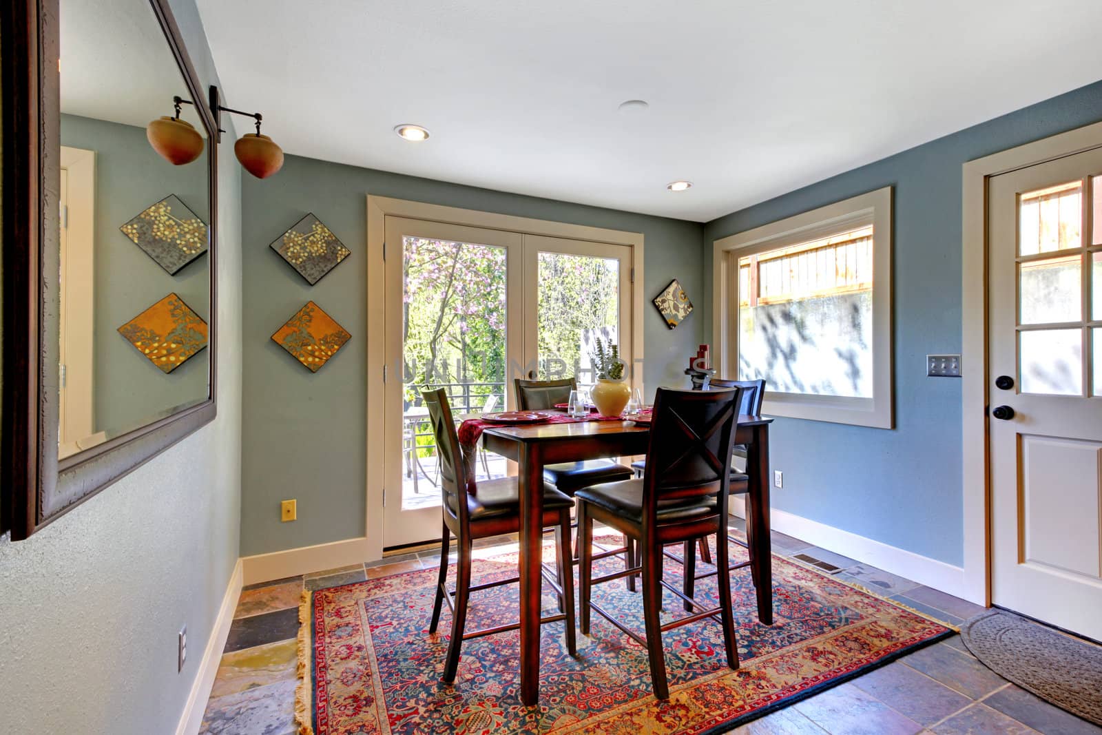 Blue bright dining room with red rug and high table.