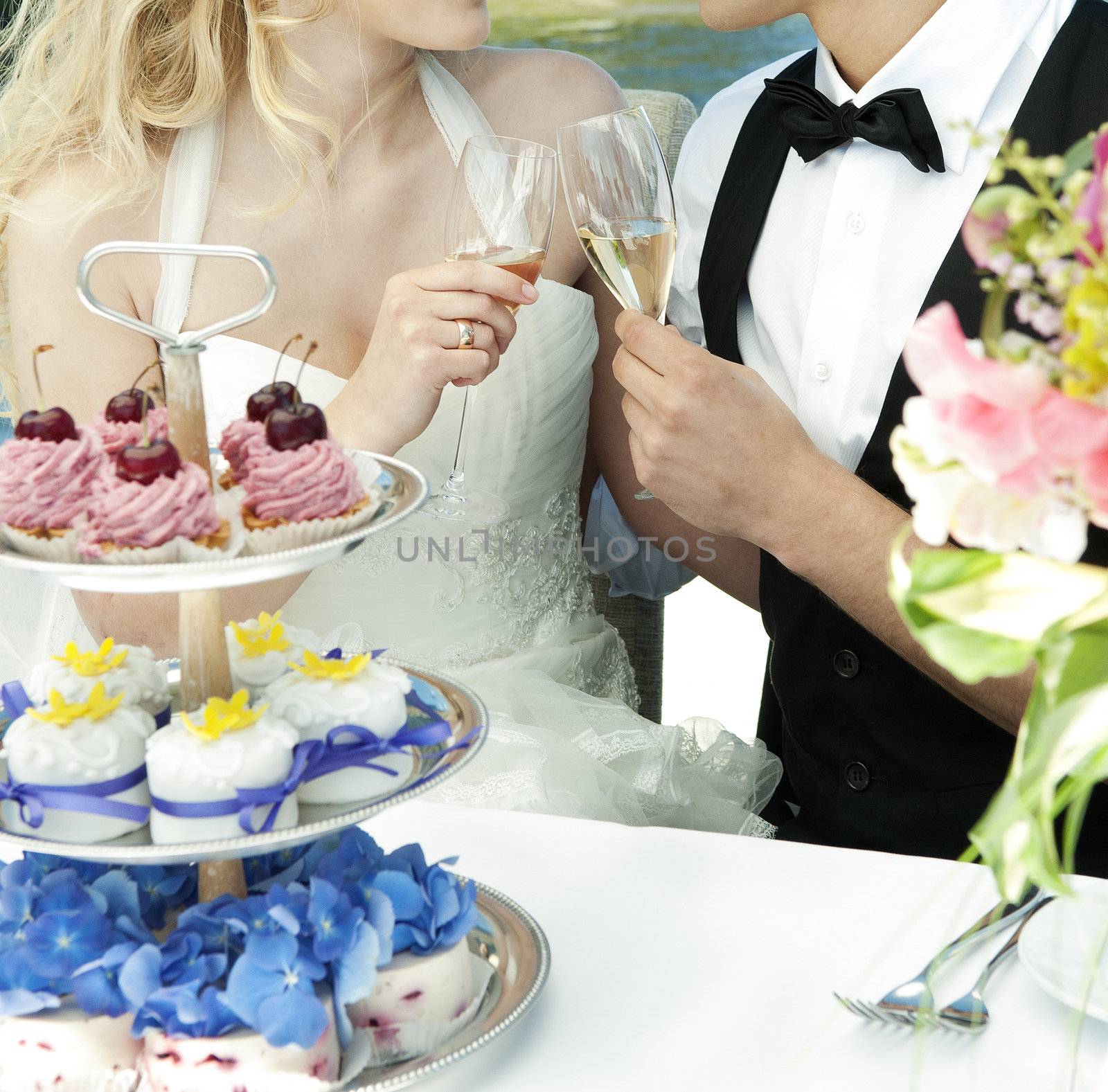 couple toasting at wedding with cakes on table