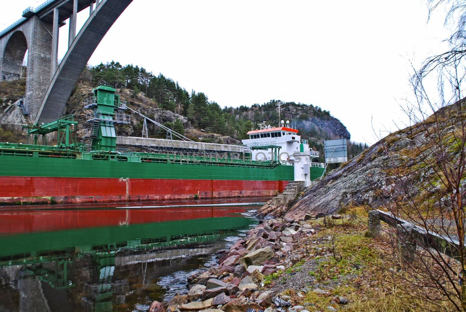 the cargo ship "sunnanhav" sailing under svinesund bridge on the way out of ringdalsfjord and to open sea, the ship has discharged its cargo in the port of halden, image is shot in november 2012 under svinesund bridge, some facts about the ship: ship type: cargo, length x breadth: 114 m X 16 m, gross tonnage: 5325, deadweight: 9402 t, flag: faroe is [fo]