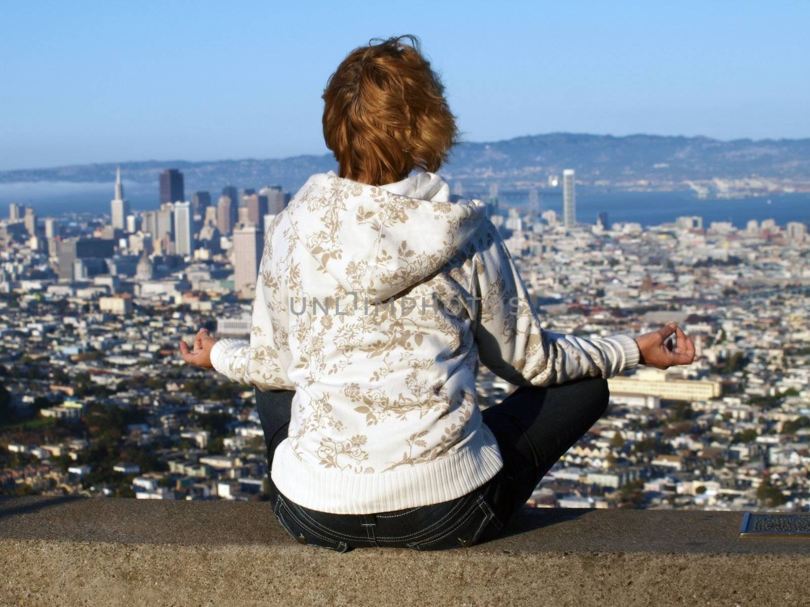  The woman meditates  on a background of Twin Peaks, San Francisco. 