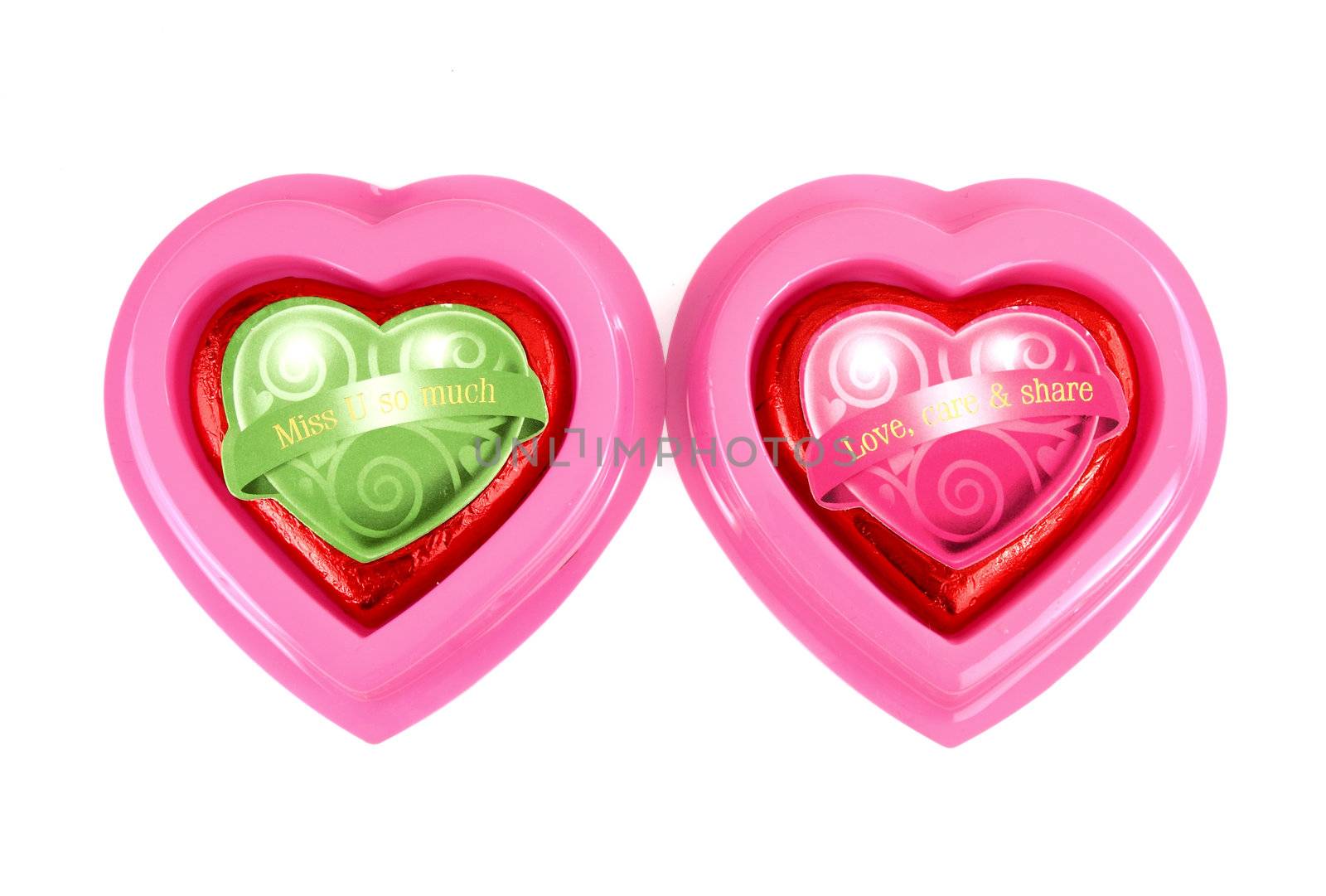 Wrapped red chocolate hearts on white background