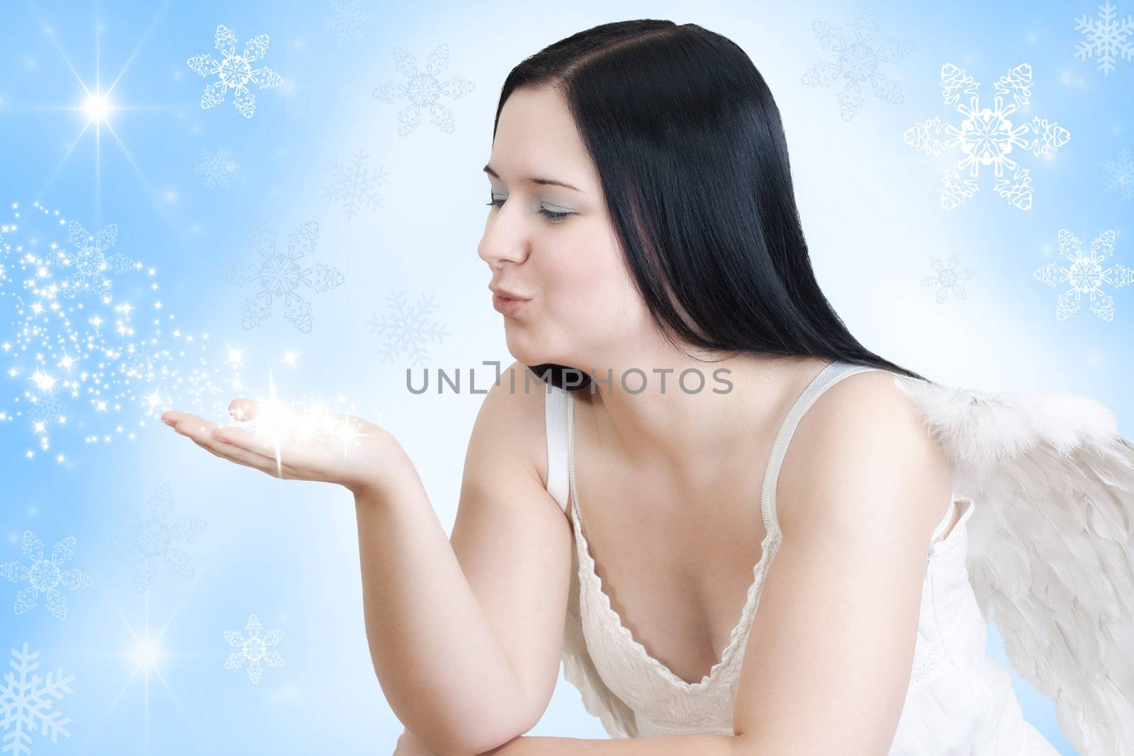 christmas angel with black hair and wings  blowing some stars on blue white background with stars and snow
