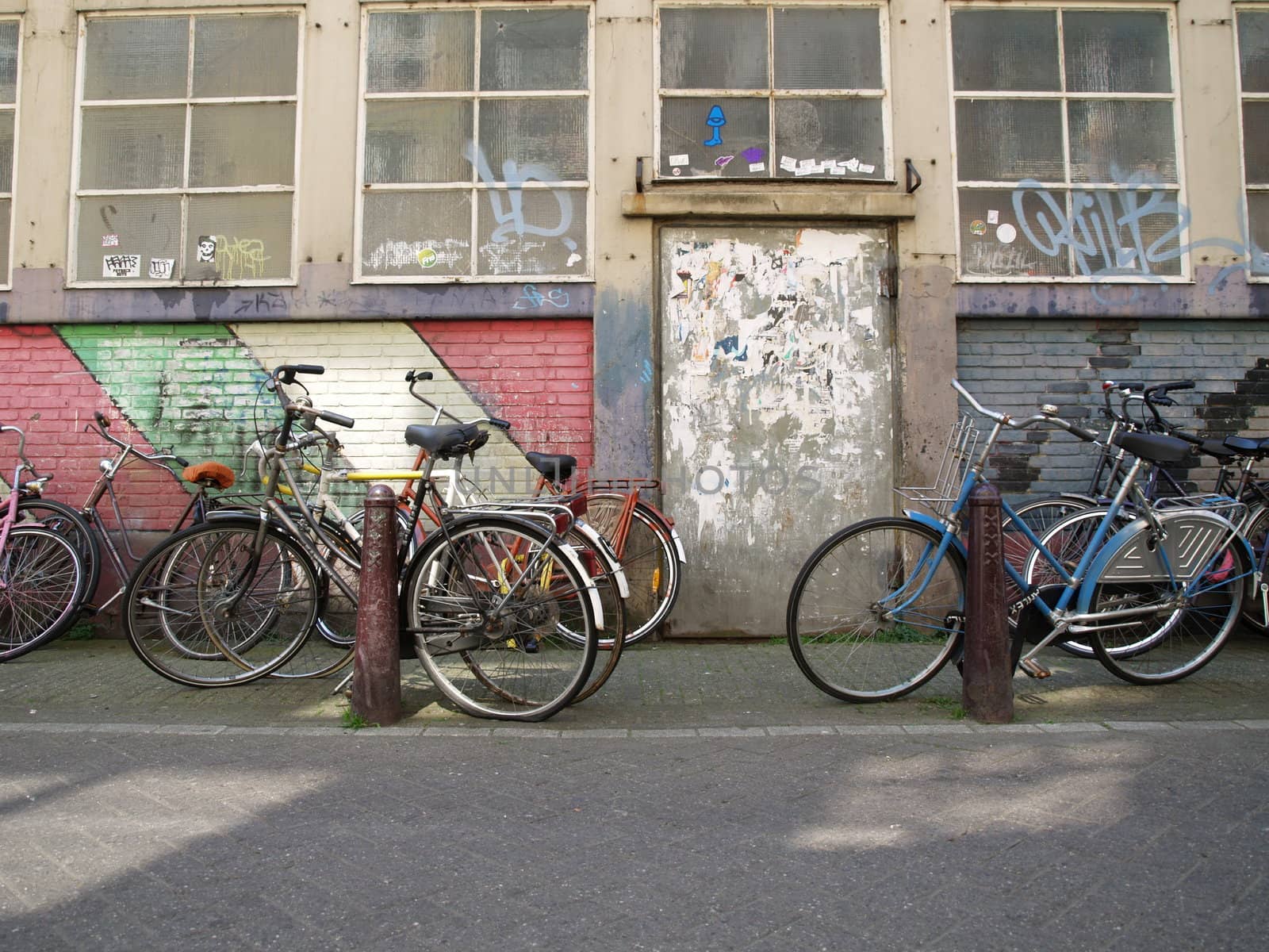 Empty bicycles in front of a colored wall.