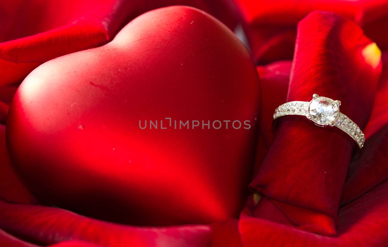 Golden diamond ring and red rose petals 