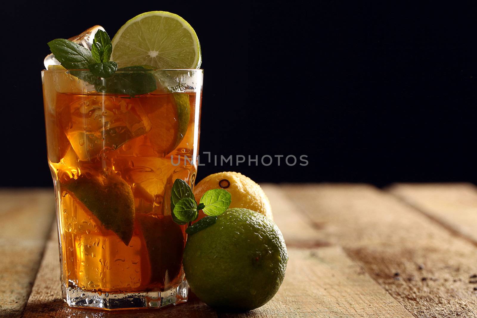 Fresh cold tea with lime, mint and lemon on a wooden surface