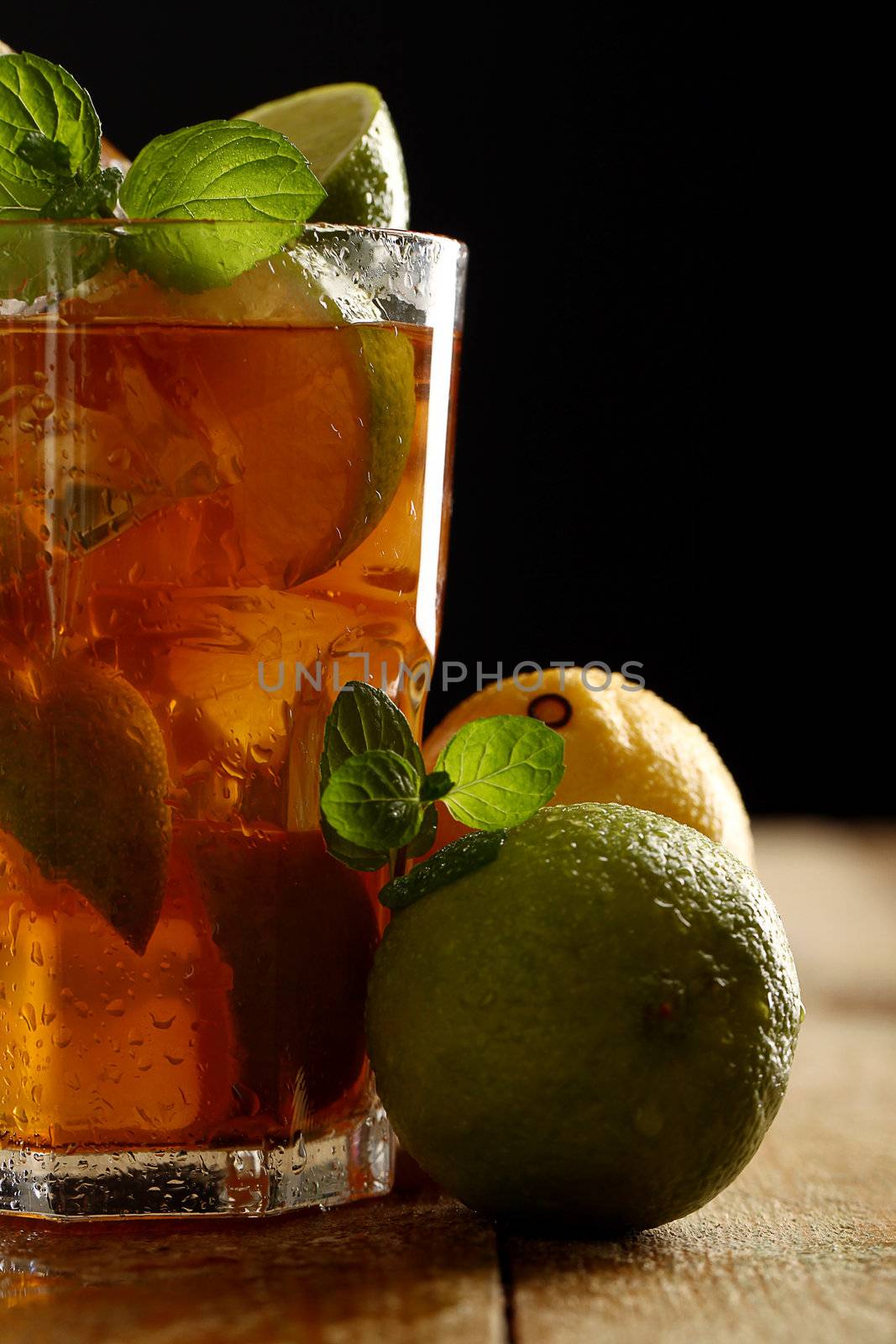 Fresh cold tea with lime, mint and lemon on a wooden surface