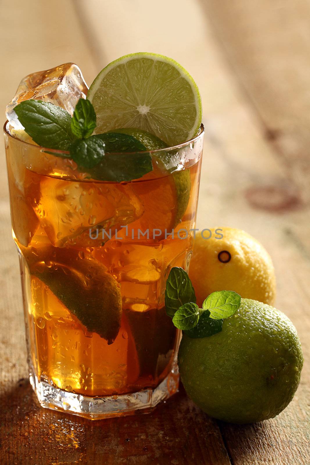 Fresh cold tea with lime, mint and lemon on a wooden surface