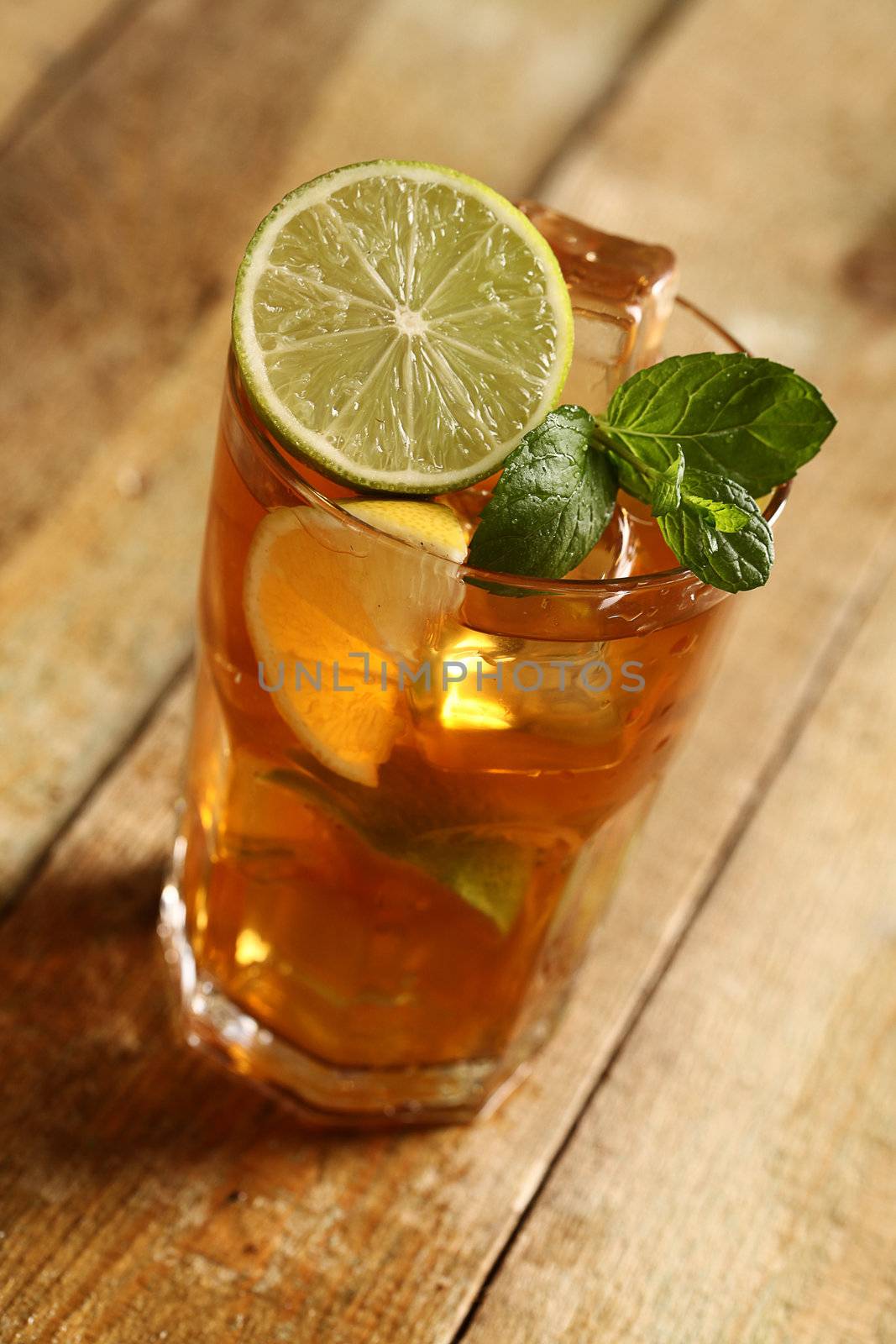 Fresh cold tea with lime, mint and lemon on a wooden surface