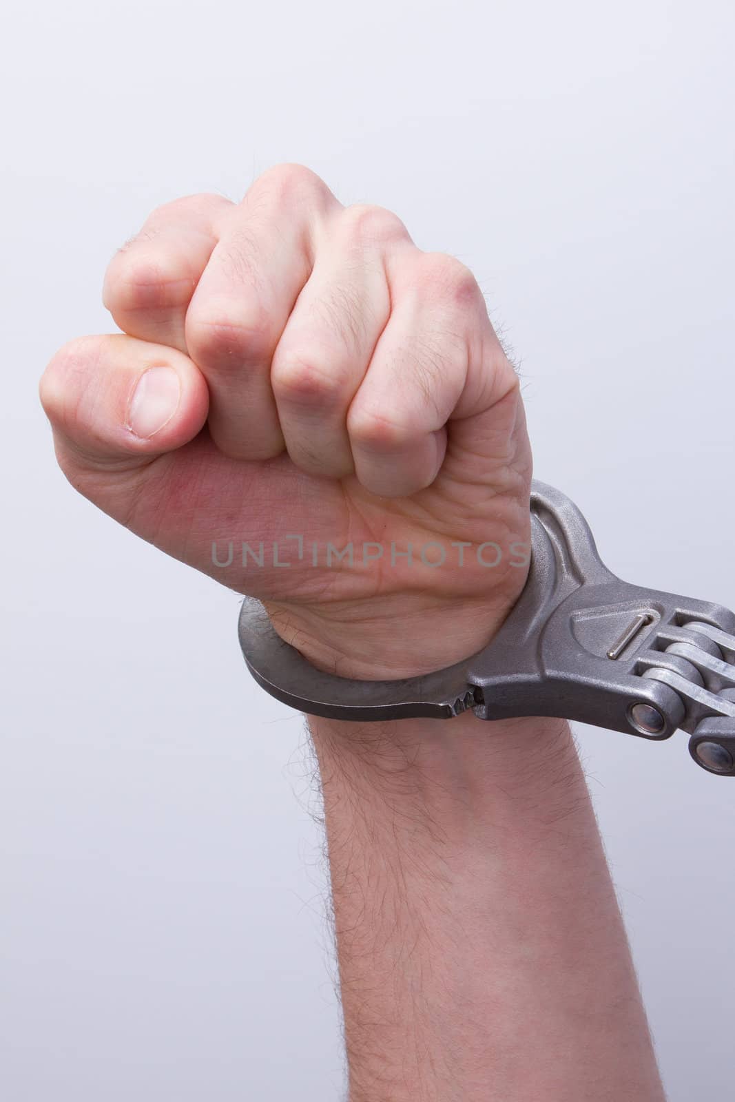 A man in metal handcuffs on a grey background