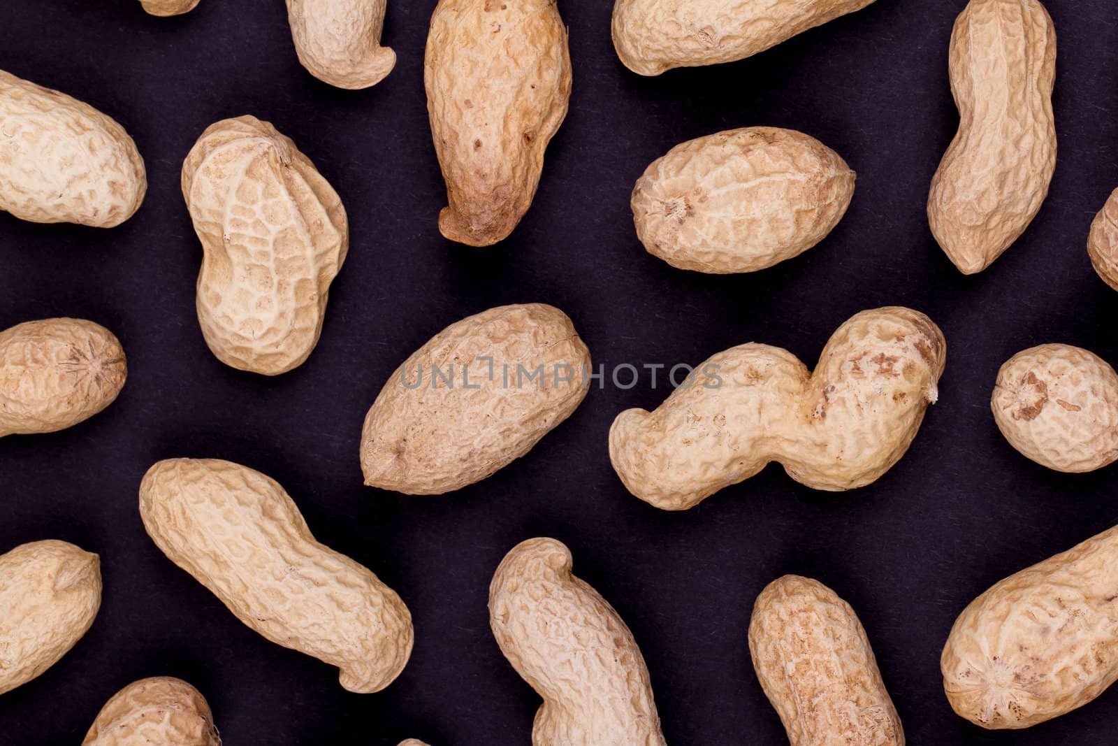 Roasted in-shell peanuts on a black background