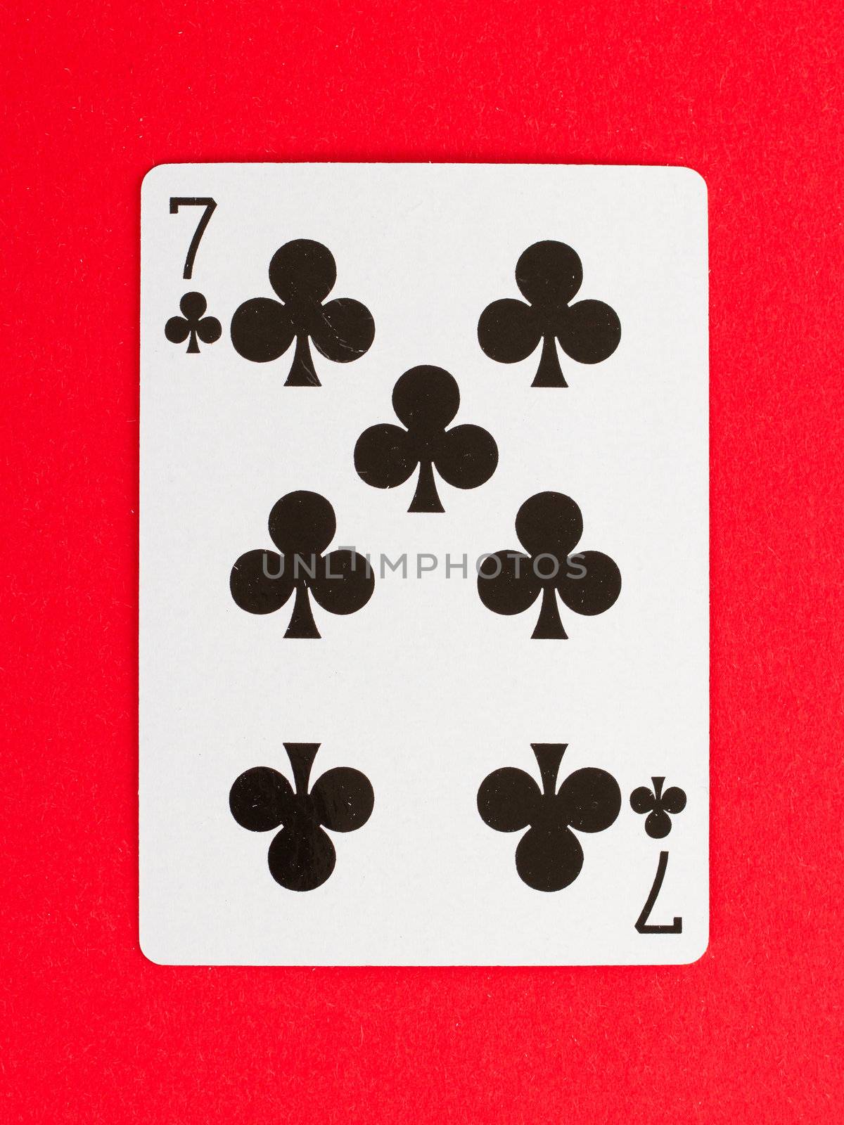 Old playing card (seven) isolated on a red background