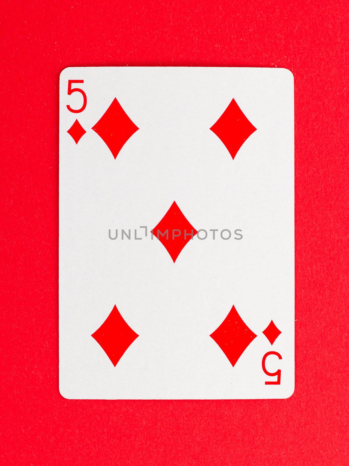 Old playing card (five) isolated on a red background
