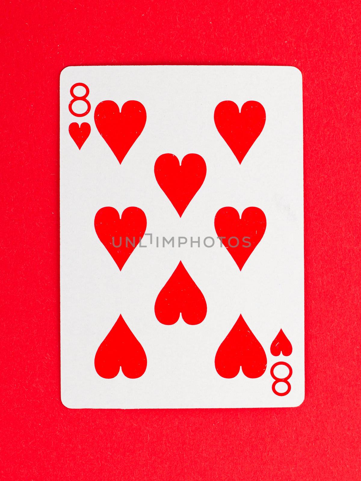 Old playing card (eight) isolated on a red background