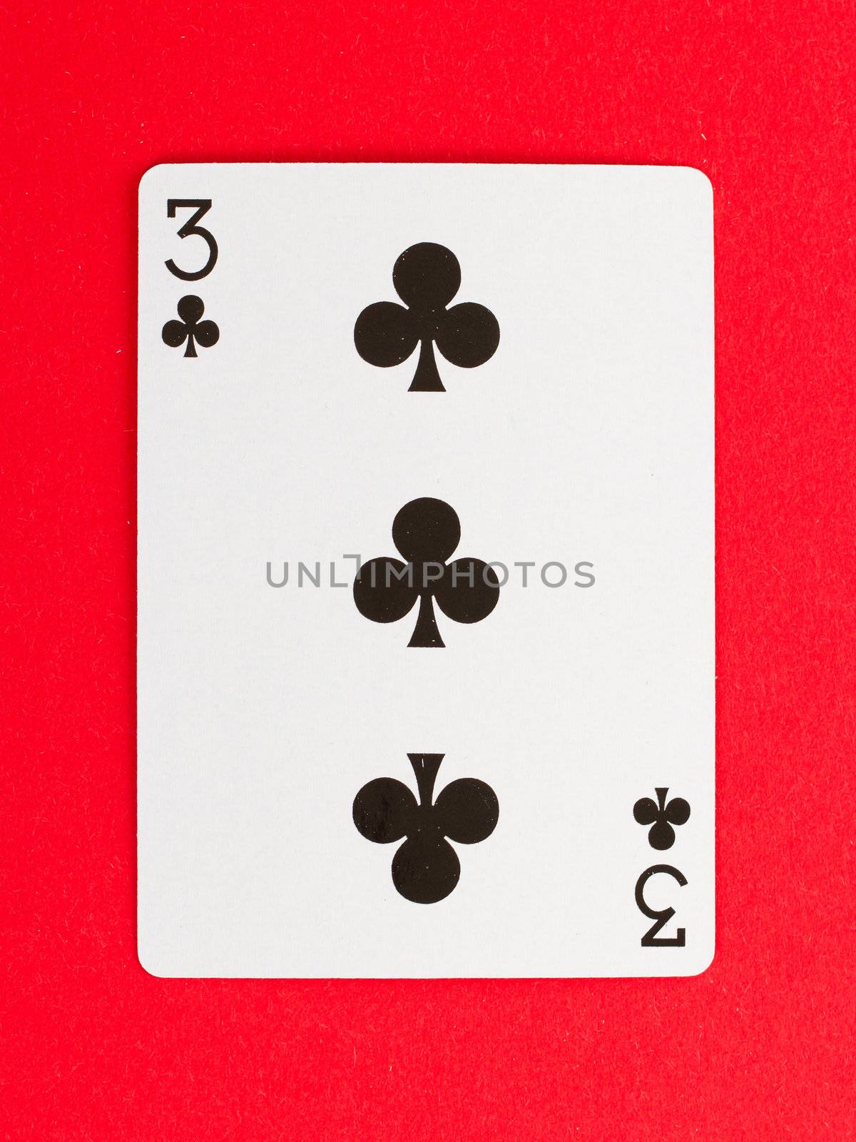 Old playing card (three) isolated on a red background