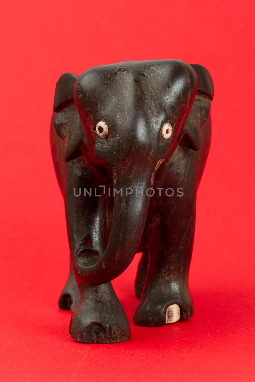 Very old ivory statue of an elephant isolated on a red beckground