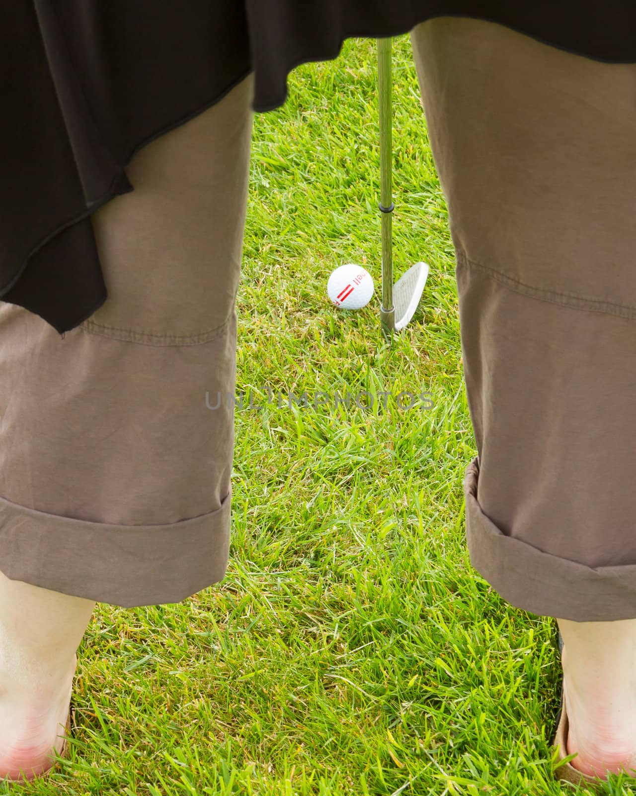 Golf player hitting the ball close-up on whole (barefoot)