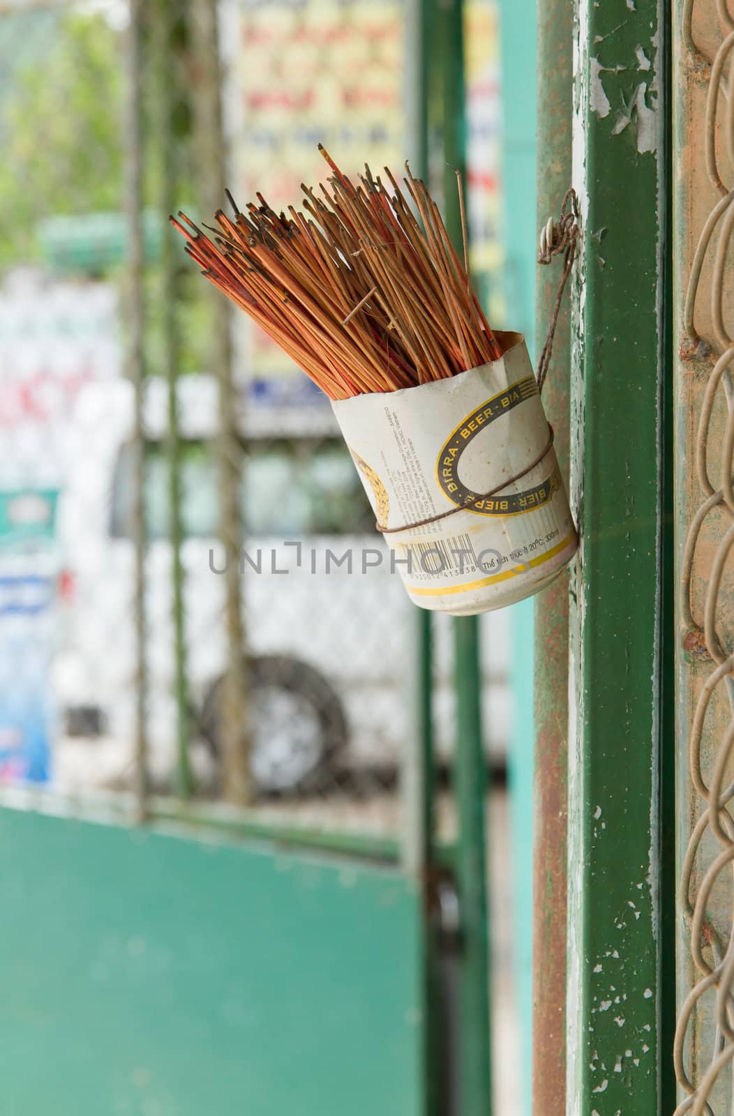 Incence sticks in an cut beer can on a wall, Vietnam
