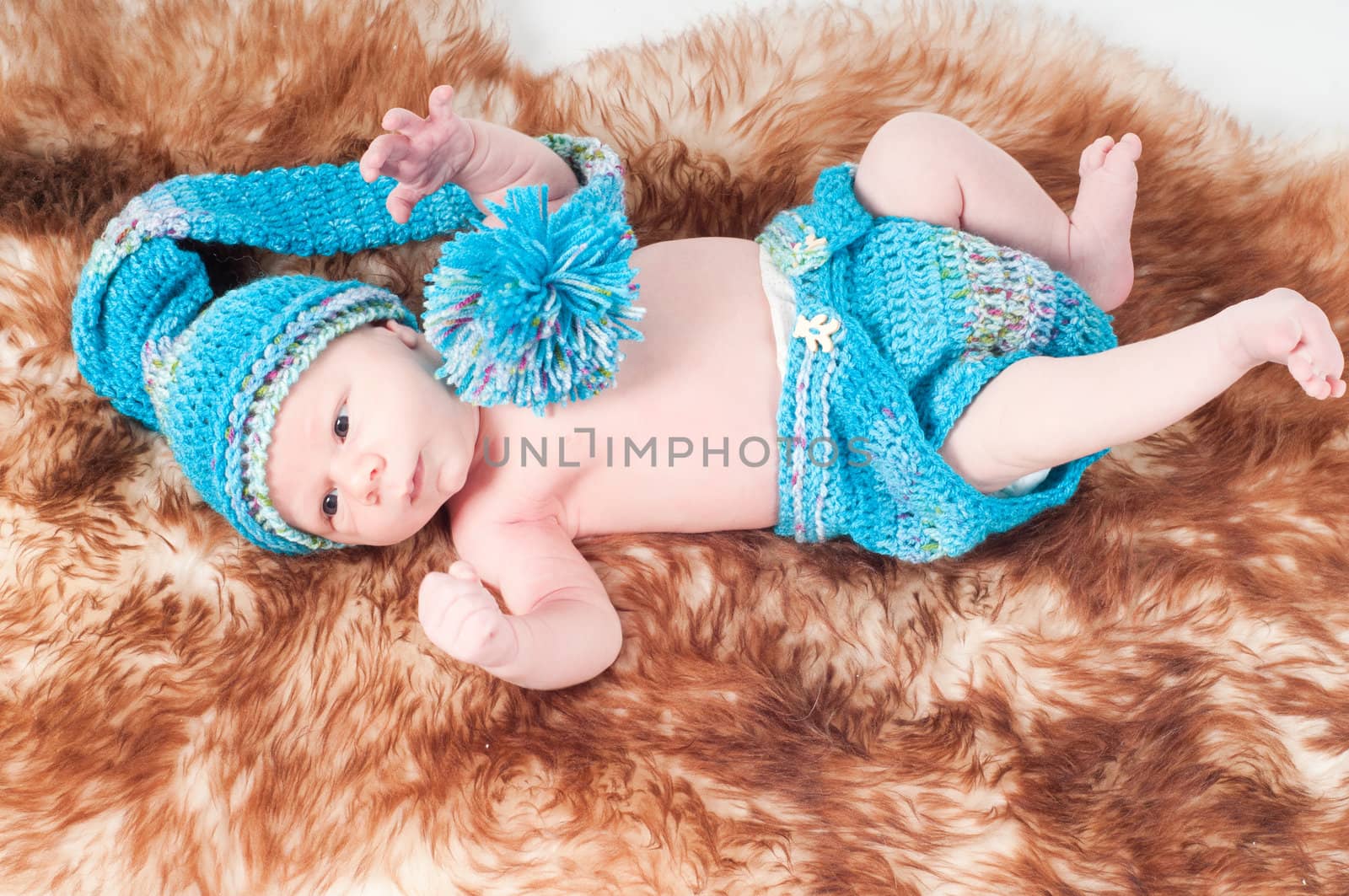 Shot of newborn baby in blue lying on fur