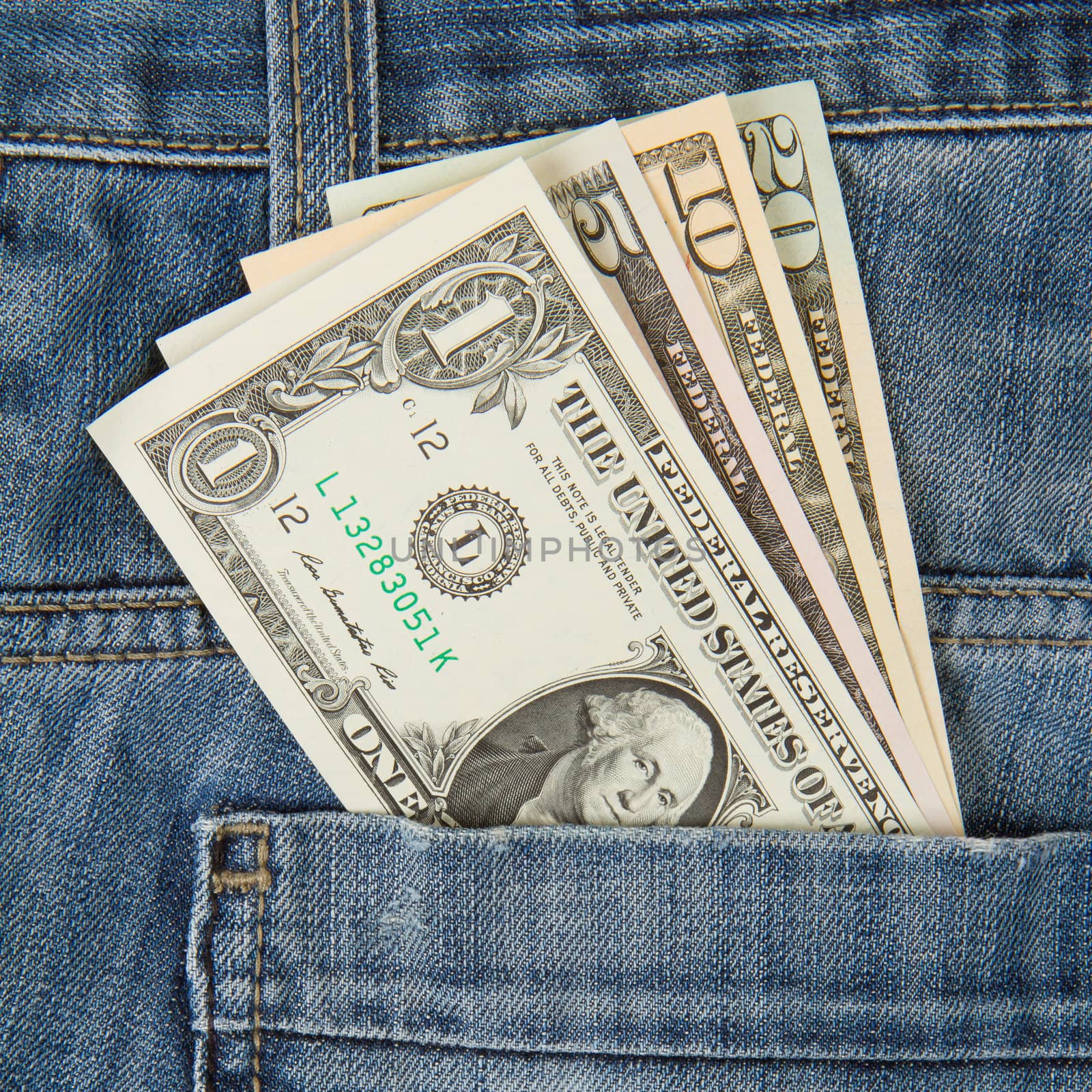 Macro shot of trendy jeans with american four different dollar bills on its pocket