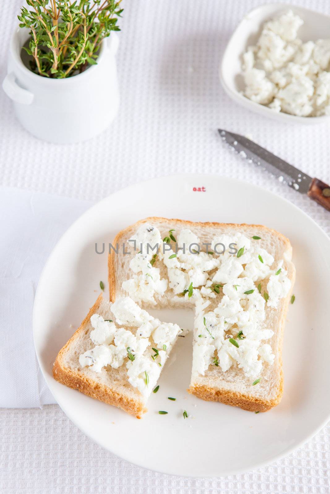 White bread sandwich with goatcheese and thyme sprinkled over it