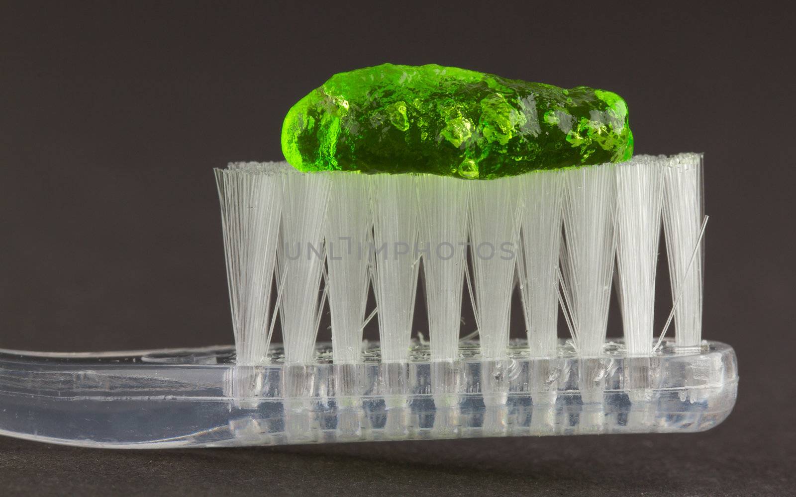 Toothbrush and green toothpaste isolated on a grey background