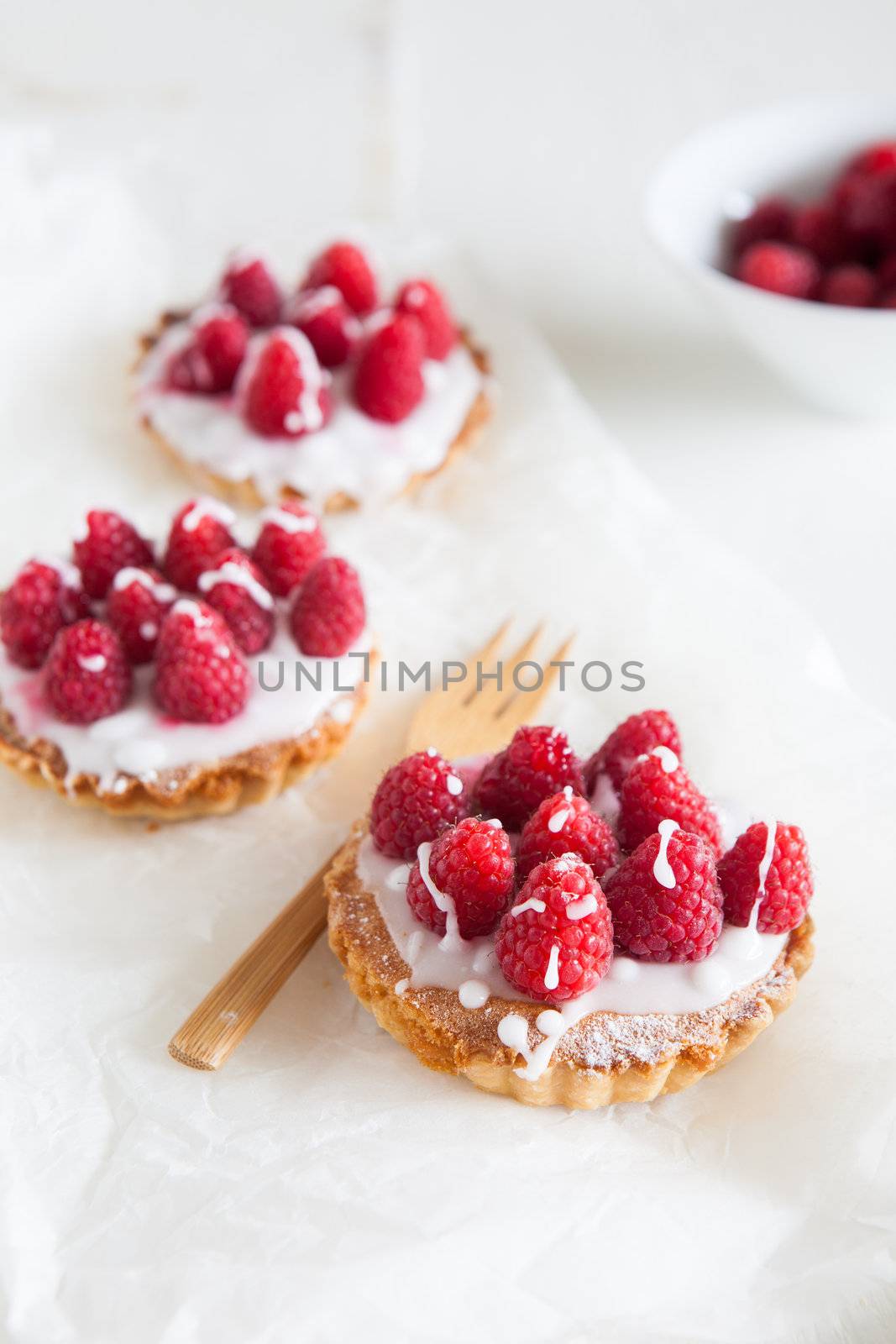 Small raspberry frangipane tarts with icing drizzed over the top